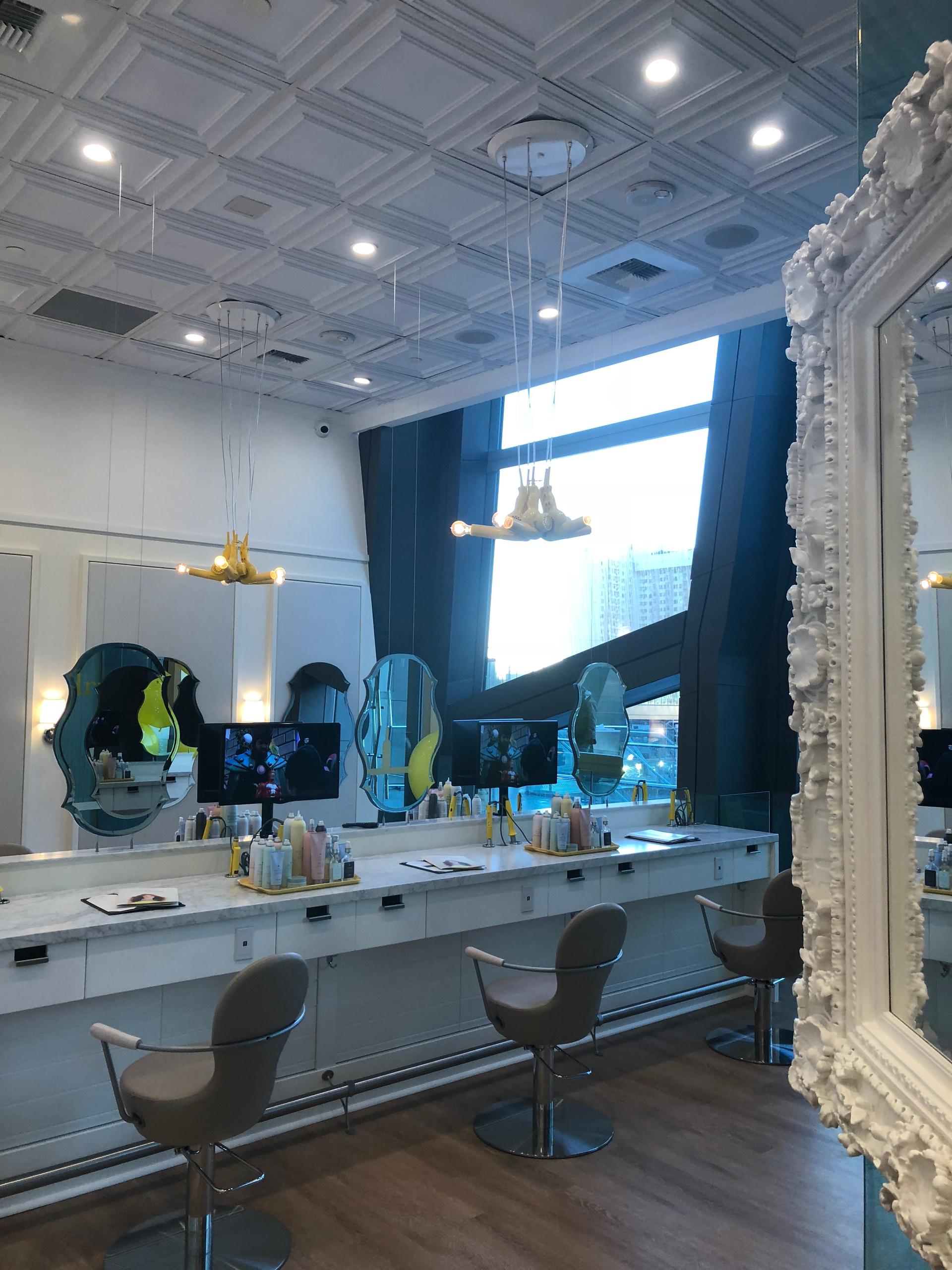 Bright salon interior with large mirror, styling chairs, and white ornate decor