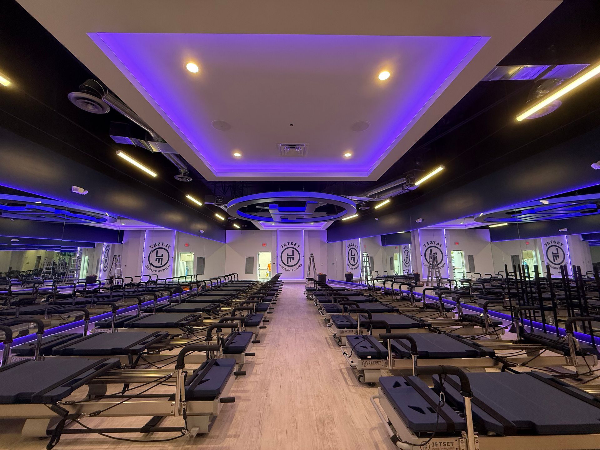 Purple-lit fitness studio with rows of exercise beds and mirrors