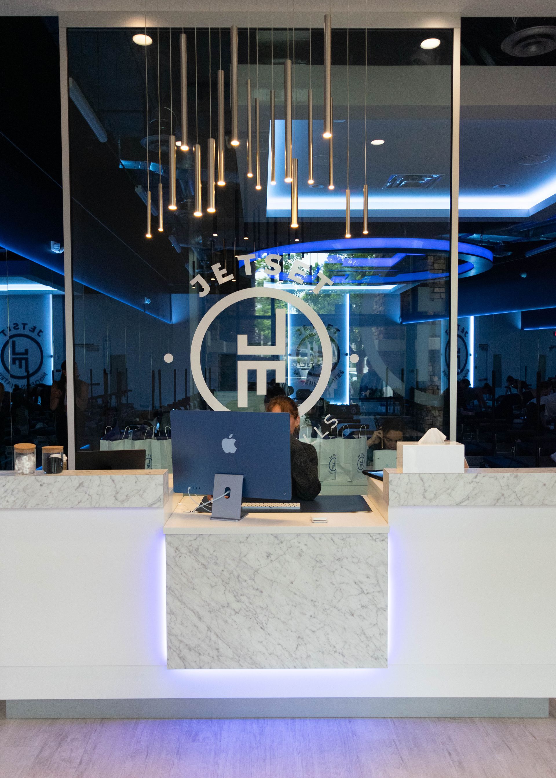 Reception desk with a person behind it in a modern office lobby lit in blue.