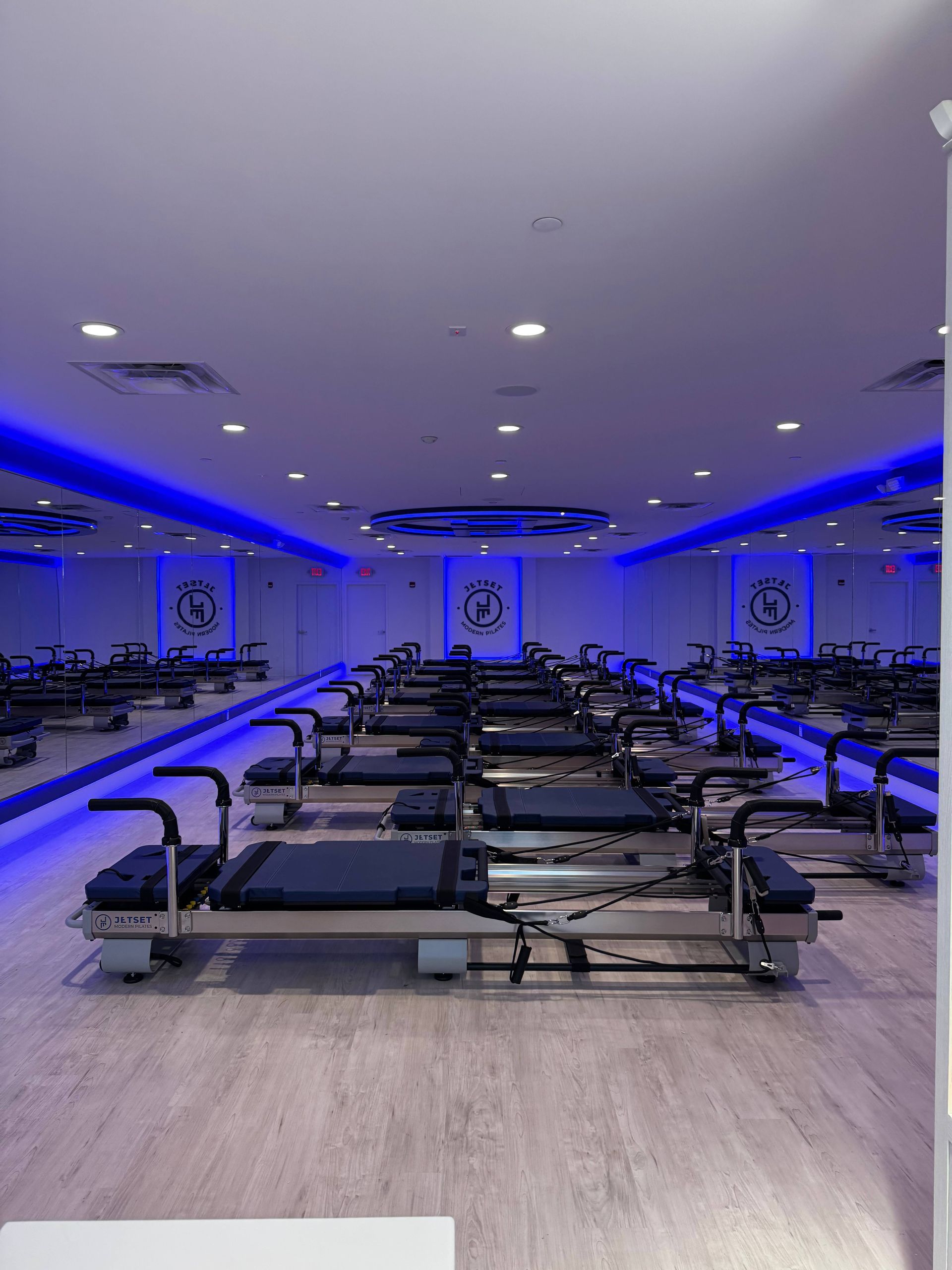 Modern Pilates studio with rows of reformer machines and blue accent lighting