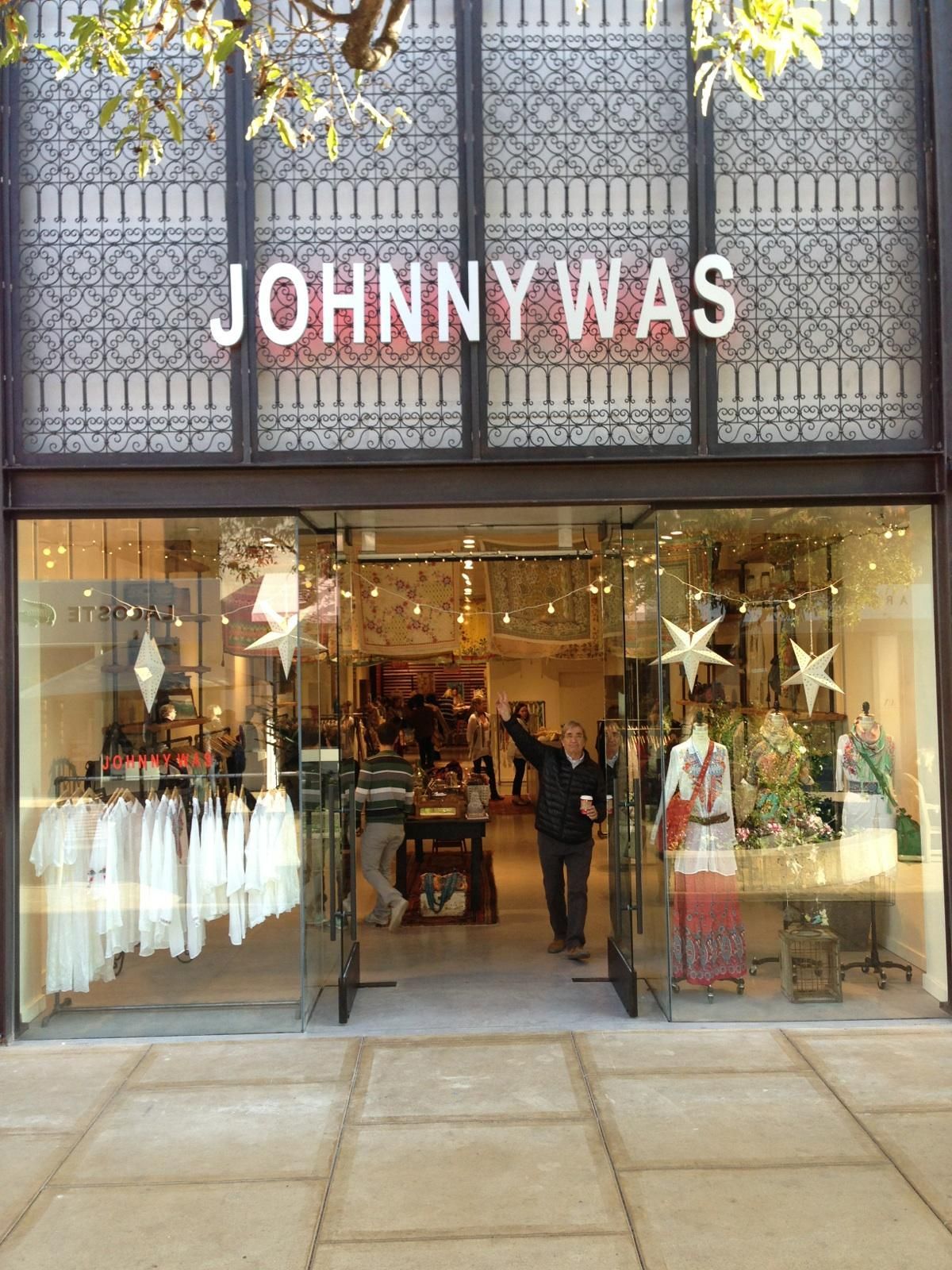 Clothing store storefront with mannequins and display windows, sign reading “JOHNNY WAS” above the entrance