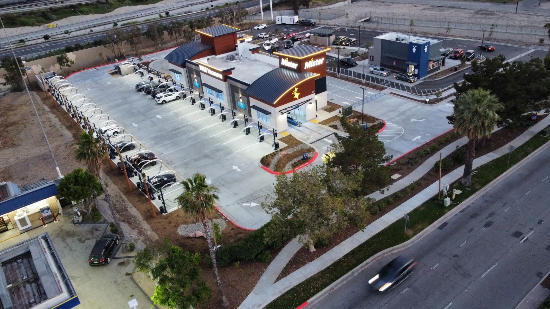Aerial view of a small commercial building with a parking lot, parked cars, and nearby roads