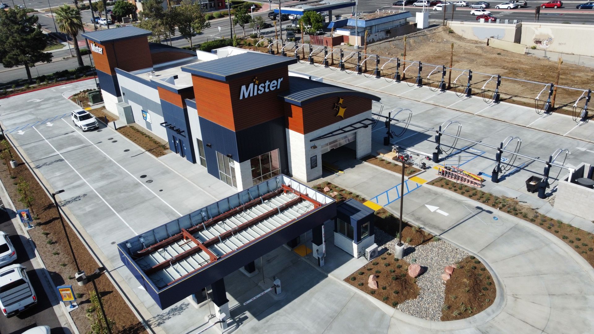 Aerial view of a Mister car wash building with drive-through lanes and parking lot.