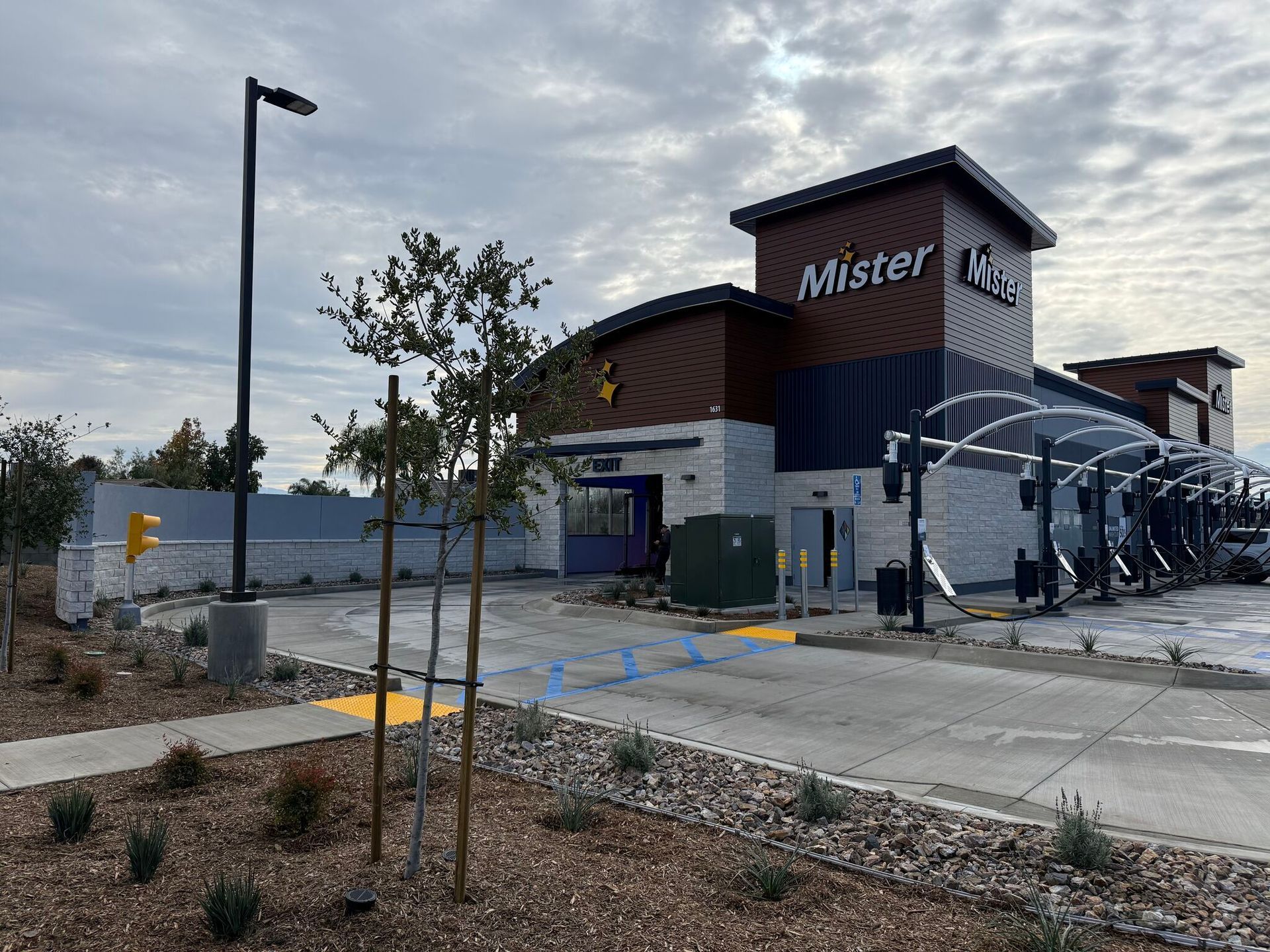 Mister restaurant exterior with drive-thru lane, dark wood building, and cloudy sky