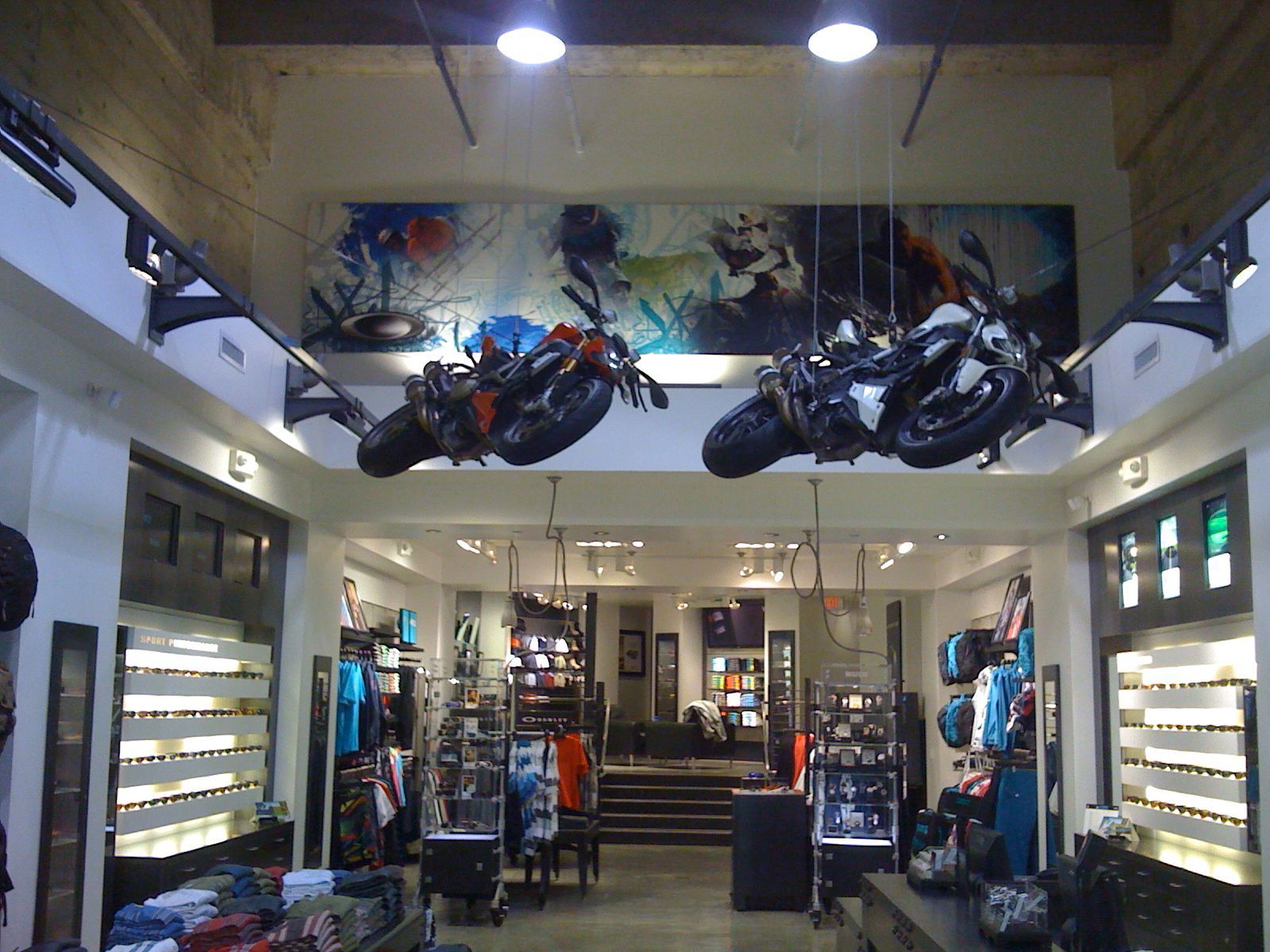 Motorcycles displayed inside a modern showroom with bright overhead lights and glass shelves