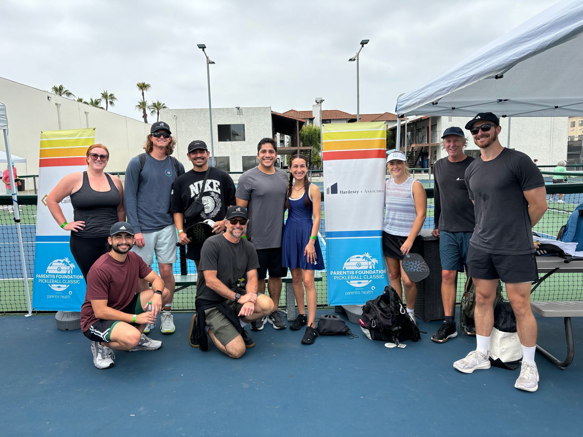 Group posing outdoors with colorful surfboards at a sports event, smiling on a blue court