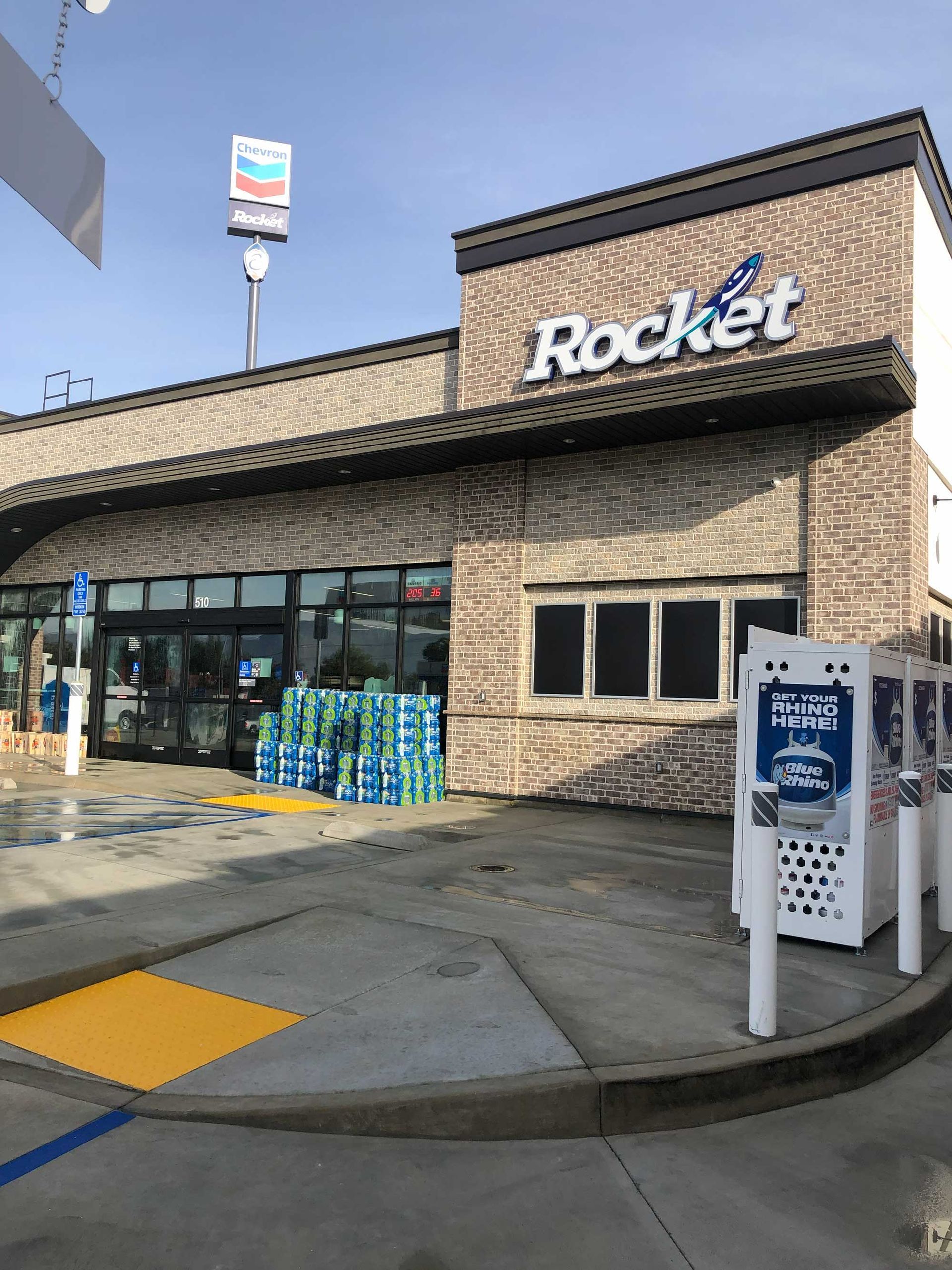 Rocket gas station storefront with blue vending machines and an air pump outside.