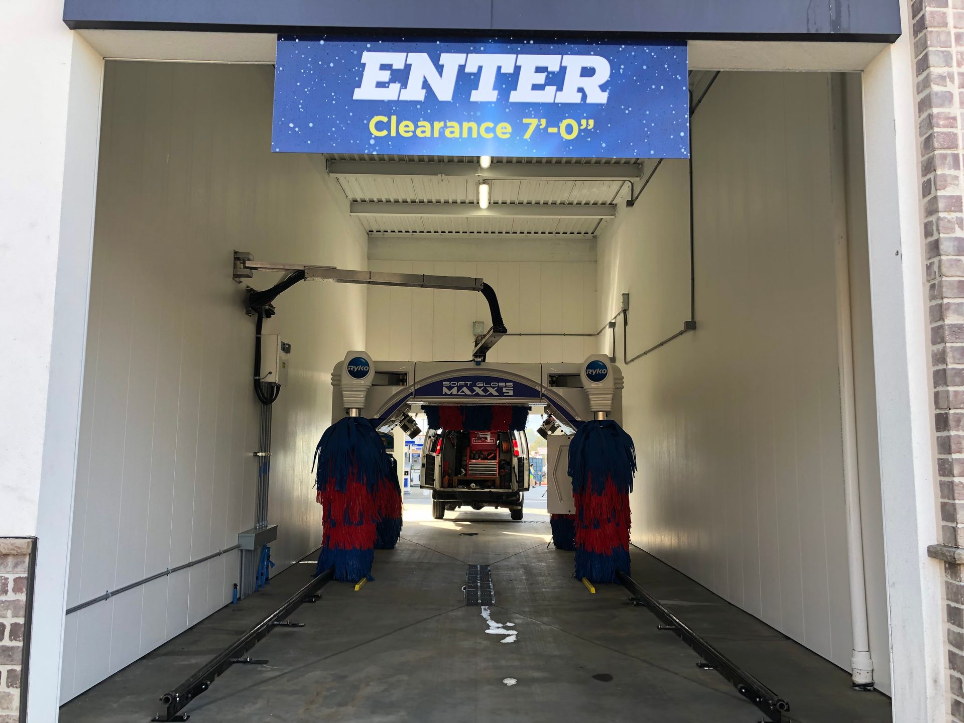 Car wash entrance with blue “ENTER” sign and 7-0” clearance, brushes visible inside.