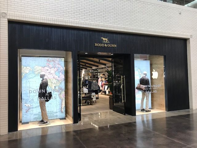 Storefront entrance with mannequins and sale posters in a mall corridor