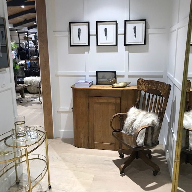 Small office nook with wood cabinet, framed art, brass cart, and a chair with a fur throw.