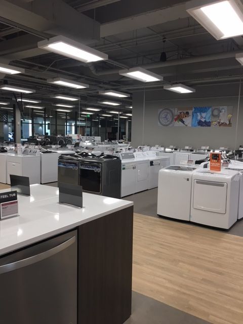 Modern office break room with white counters, coffee machines, and bright overhead lights
