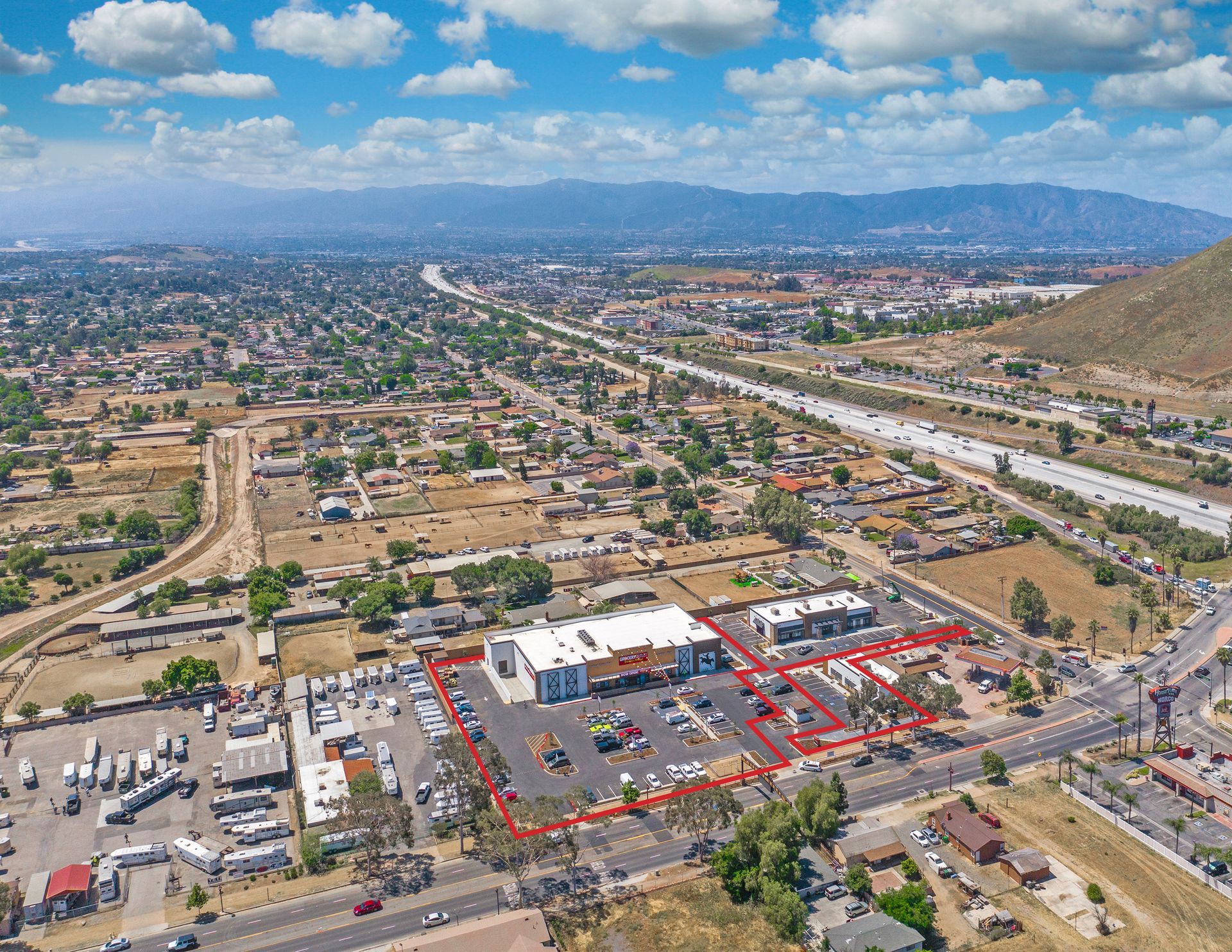 Aerial view of a city with a busy highway, neighborhoods, and mountains in the distance