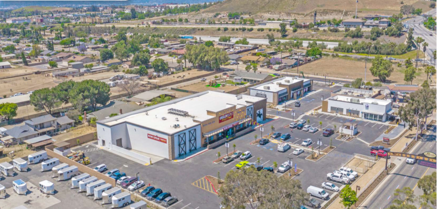 Aerial view of a shopping center with a large parking lot and surrounding roads in a suburban area