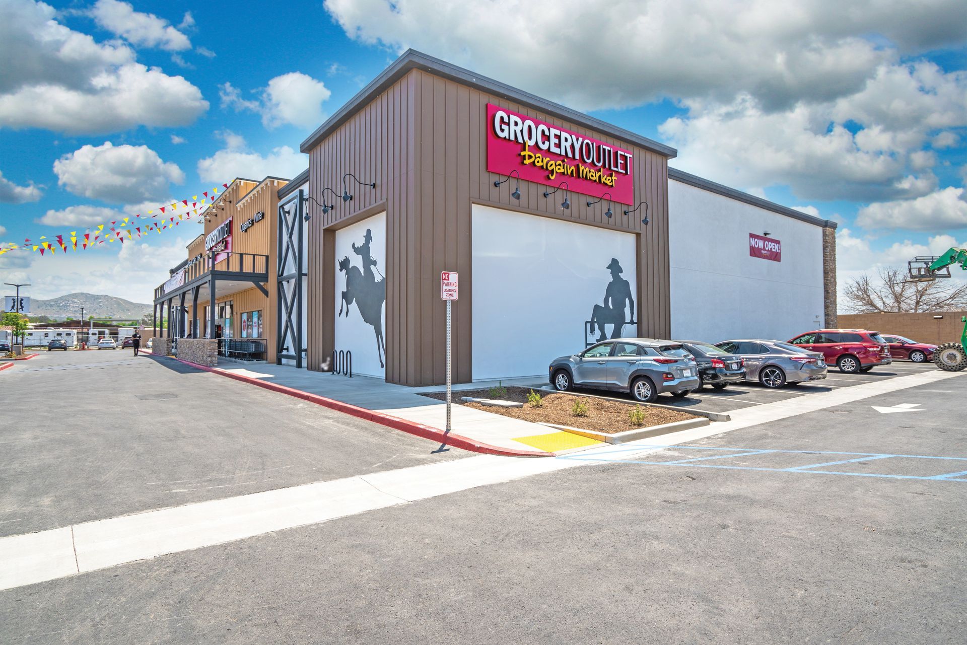 Grocery outlet storefront with parked cars on a sunny street corner