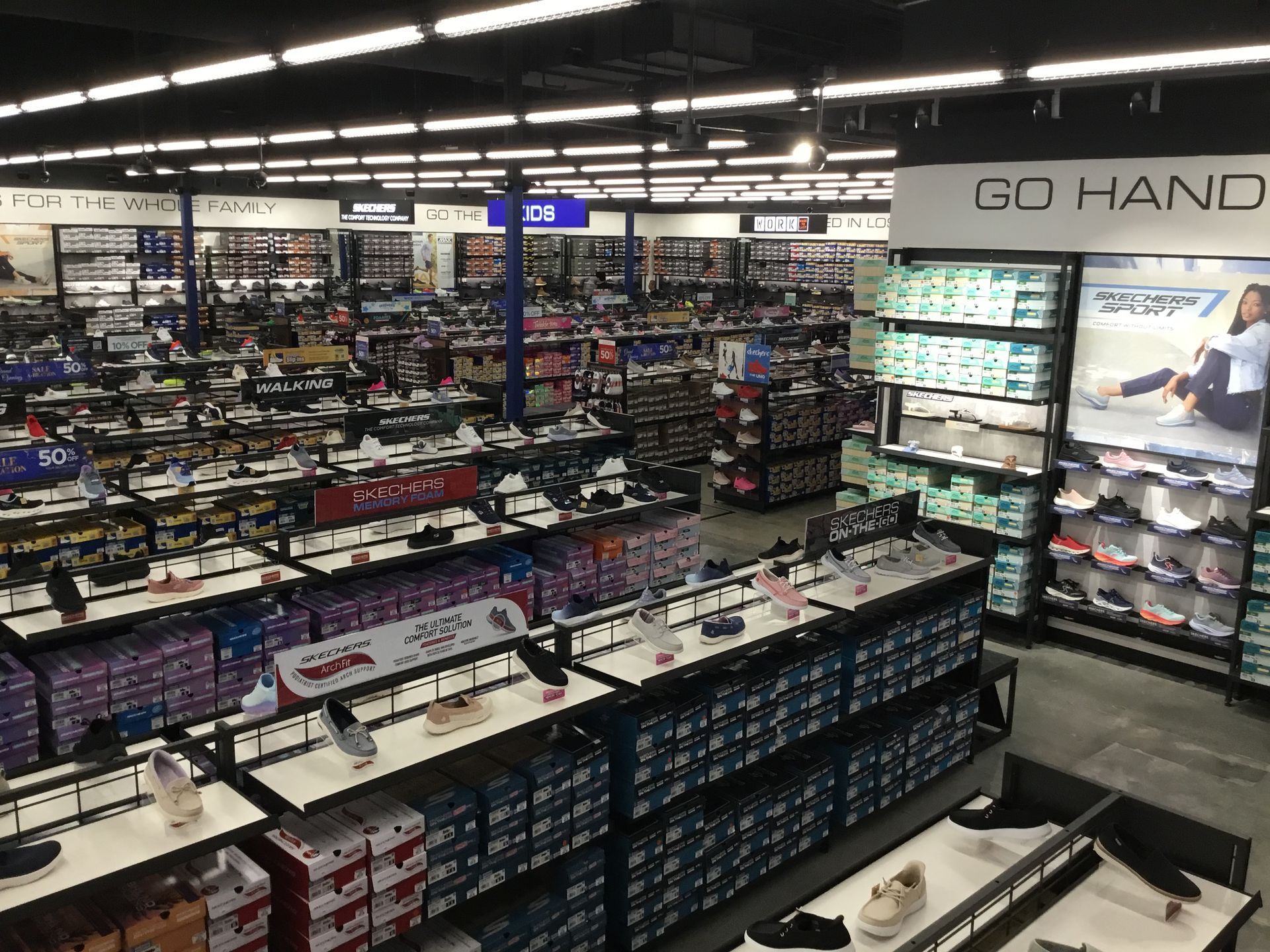 Shoe store interior with rows of sneakers and a GO HAND display wall