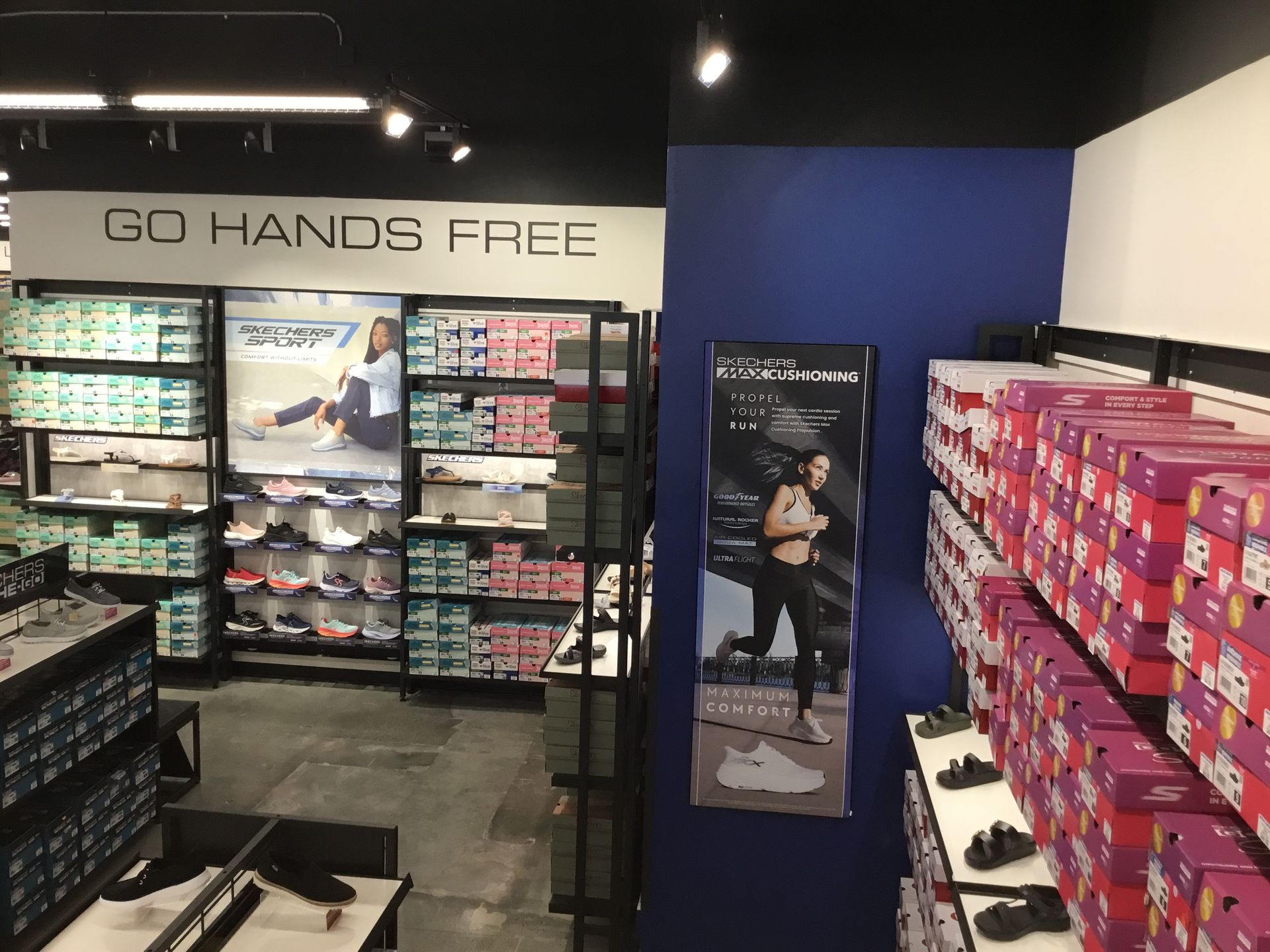 Sneaker store aisle with colorful shoe boxes and a “GO HANDS FREE” sign above the displays