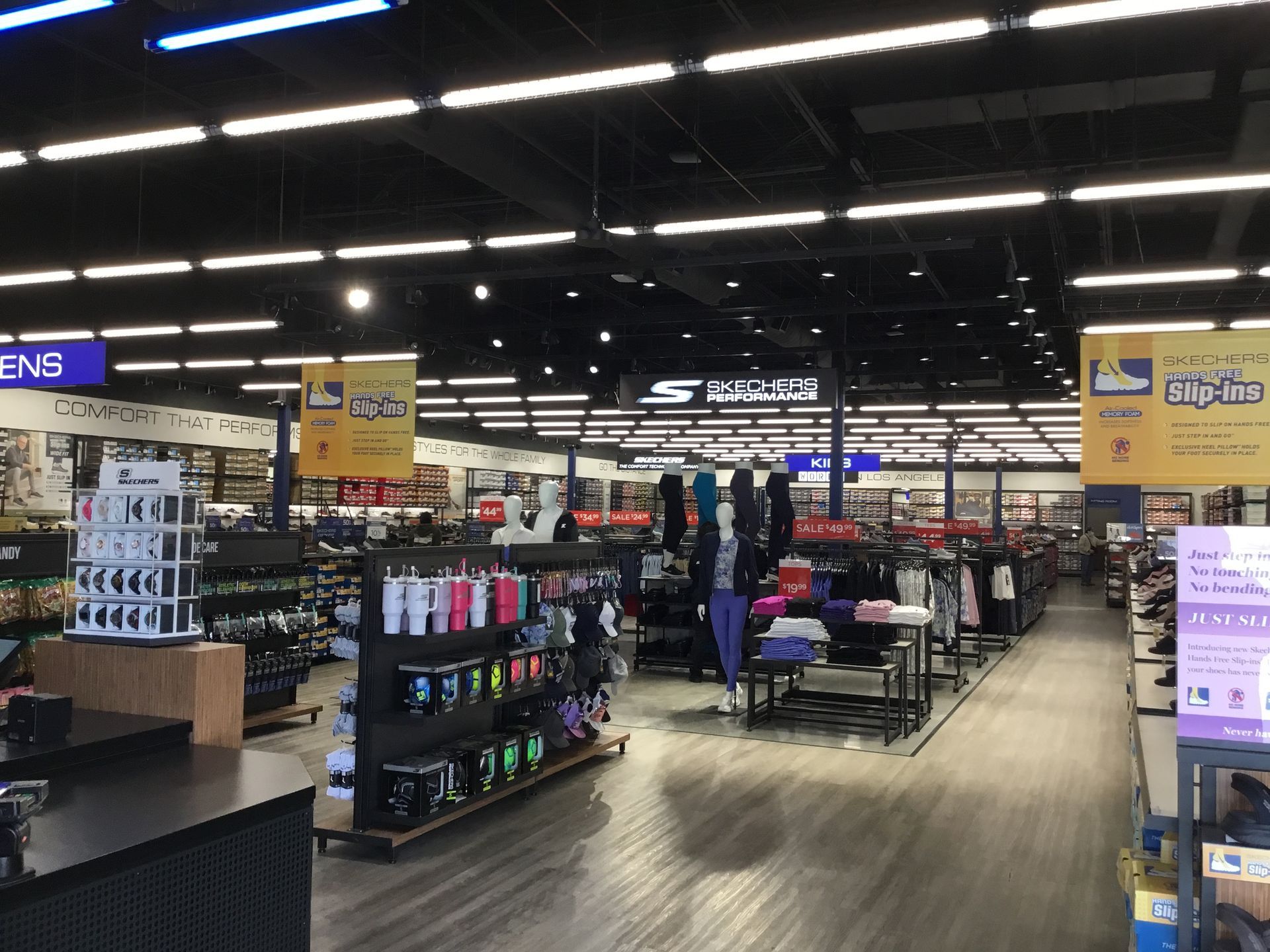 Retail store aisle with shelves of electronics and accessories under bright ceiling lights