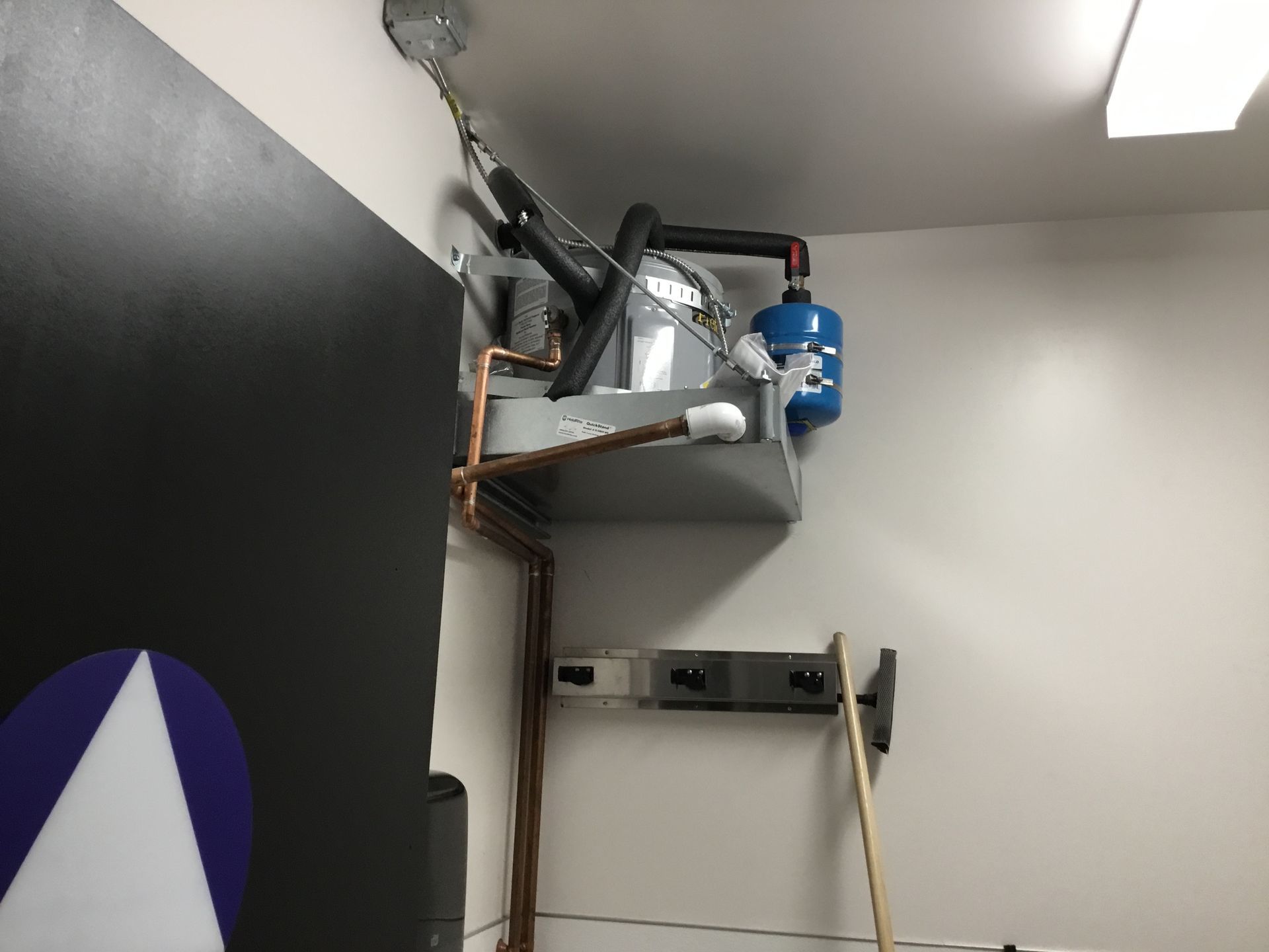Wall-mounted mechanical equipment with blue motor and exposed pipes in a utility room