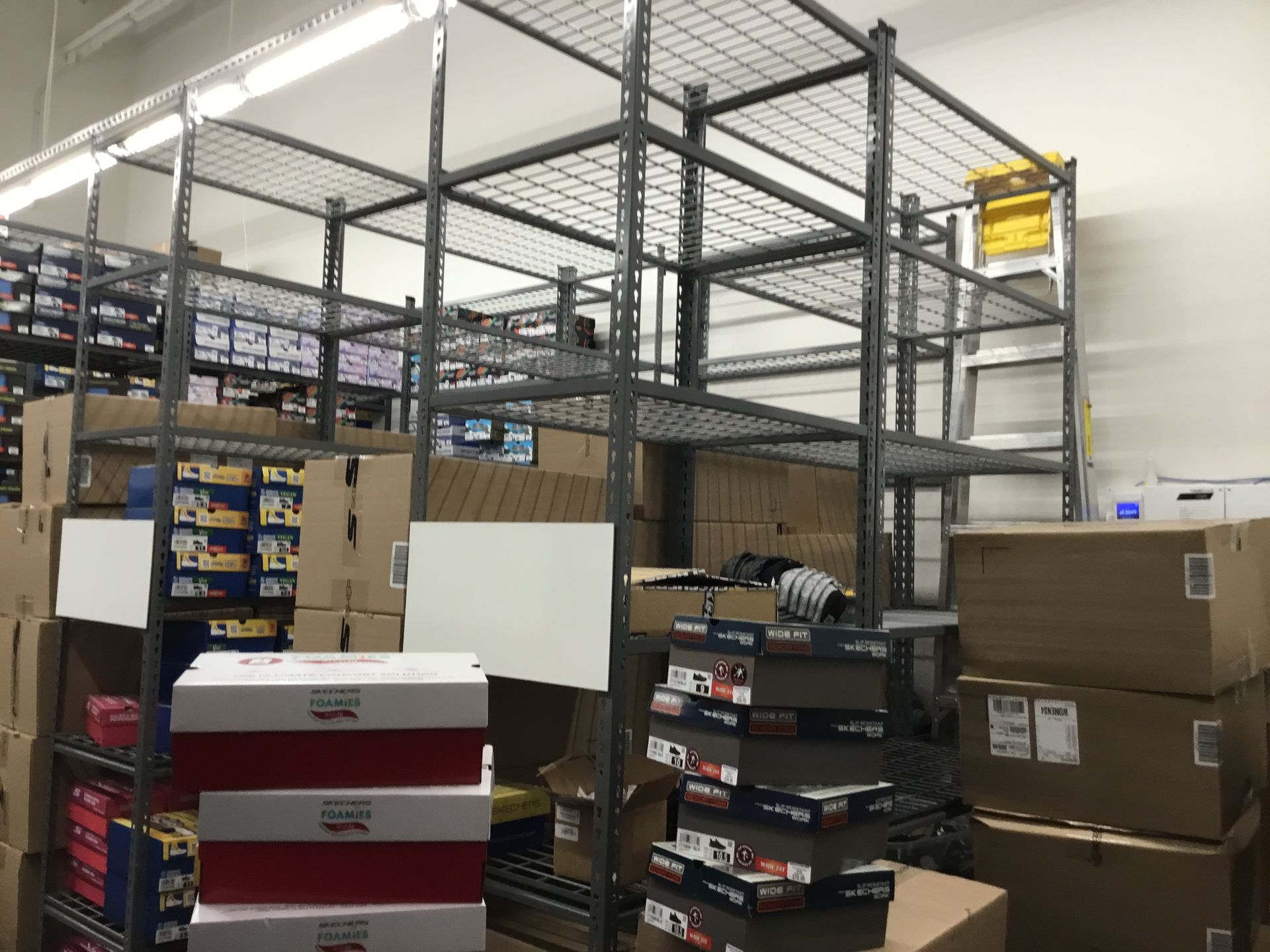 Warehouse storage area with stacked boxes, metal shelving, and cartons piled around the room