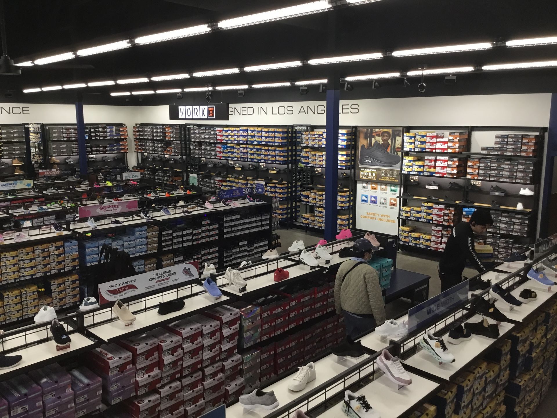 Busy retail store interior with shelves of colorful products and two customers browsing