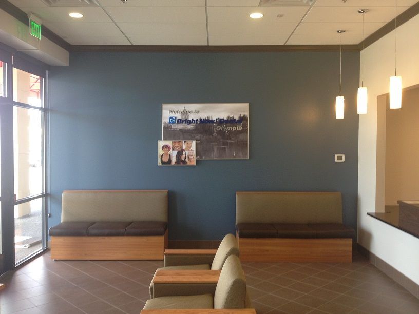 Modern lobby with blue walls, wood floor, gray benches, and hanging pendant lights
