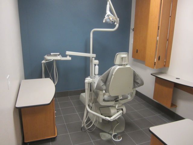 Dental exam room with chair, overhead light, cabinets, and counter tops