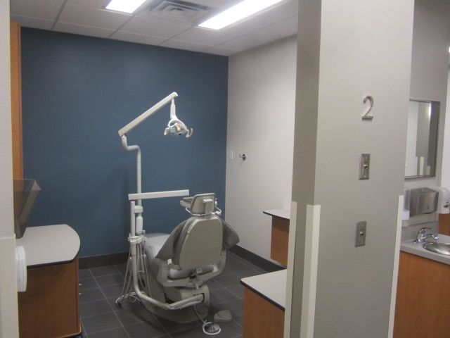 Dental exam room with chair, overhead lamp, and blue accent wall
