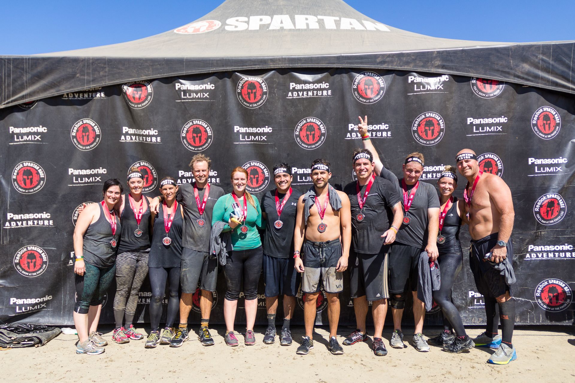 Group of athletes posing in front of a Spartan race backdrop and tent outdoors