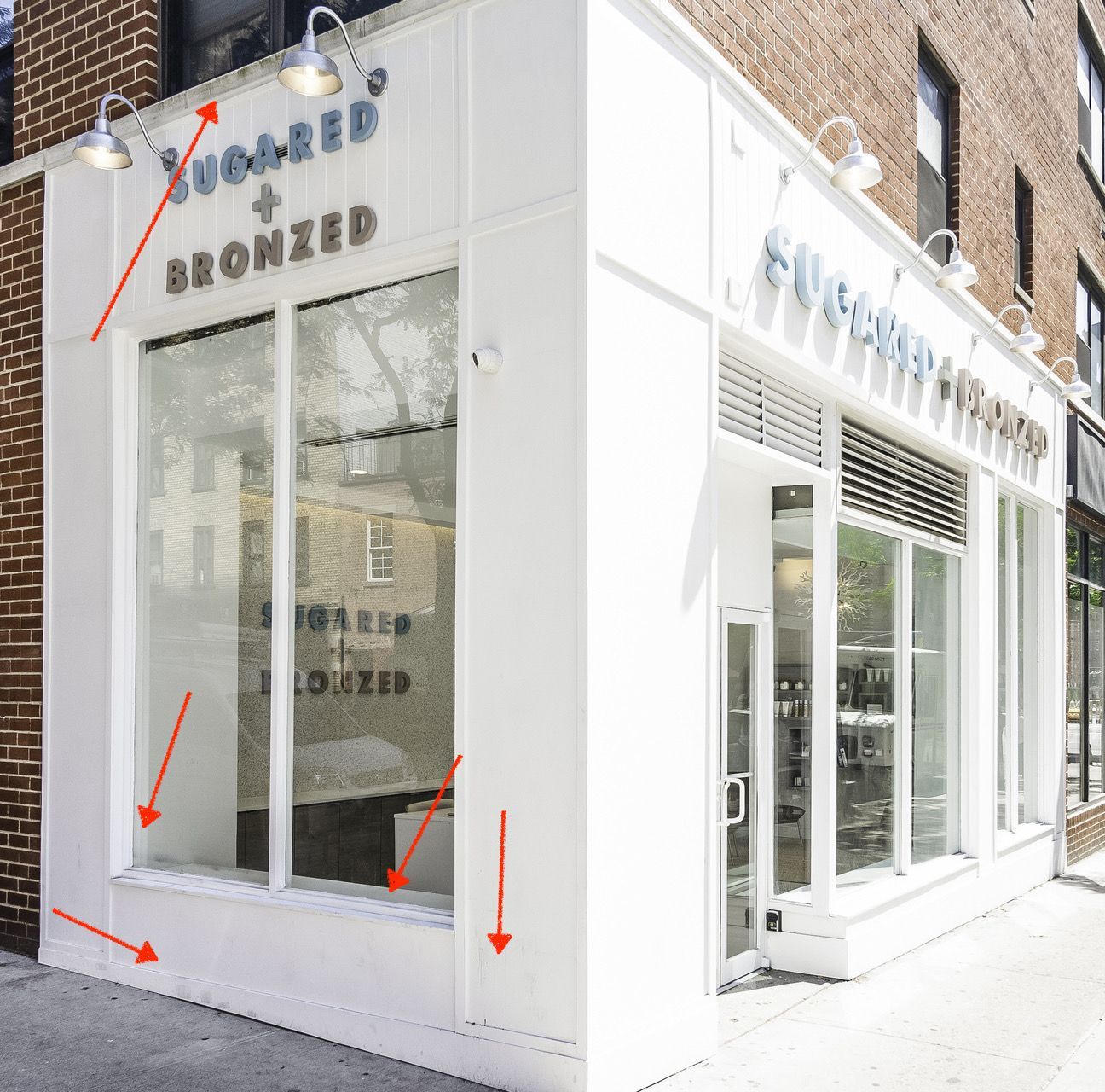White storefront with glass windows and bronze lettering on a brick street corner.