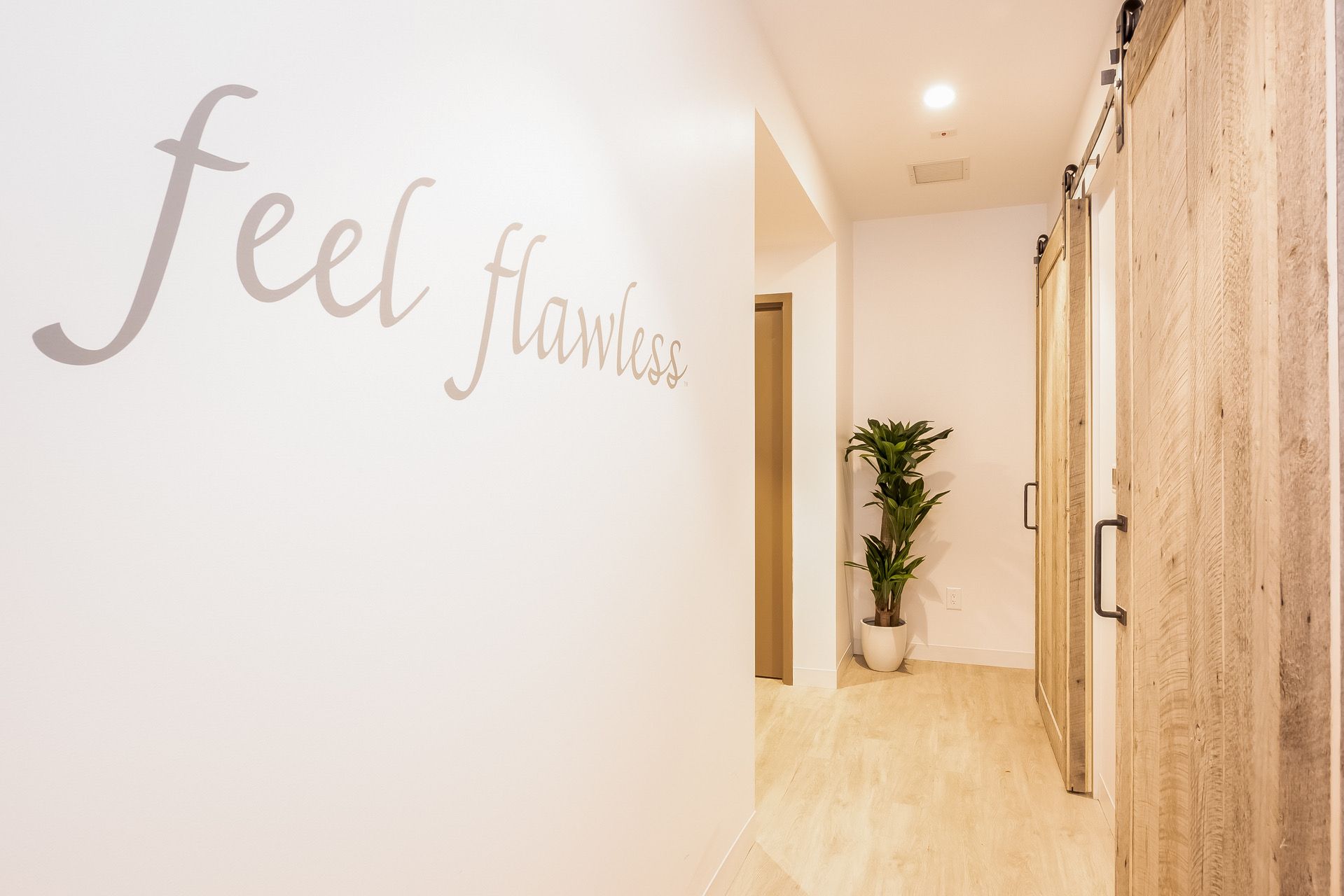 Bright hallway with light wood floors, potted plant, and wall text reading “feel fabulous.”