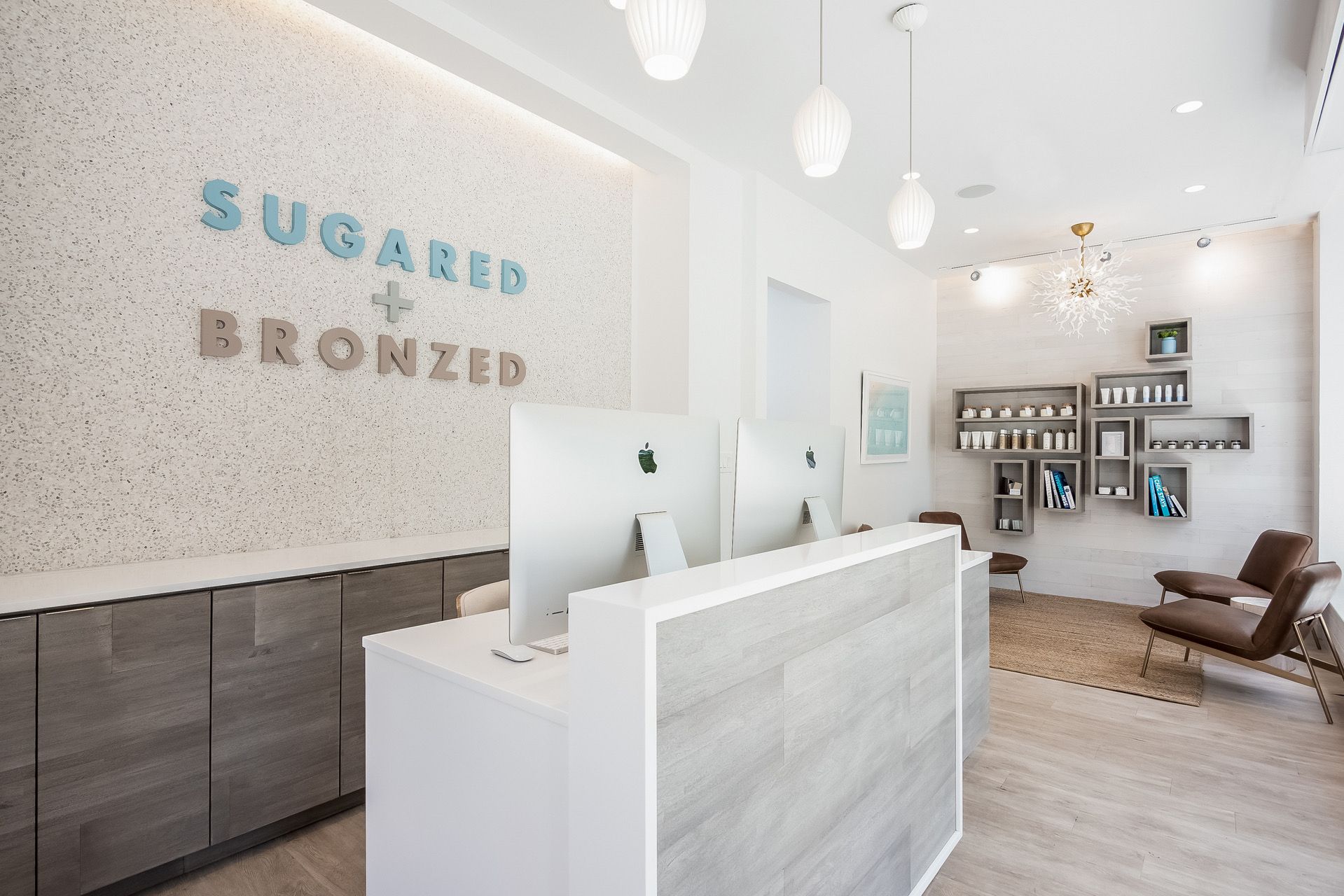 Bright modern reception area with white desk, “Squared Bronze” wall sign, and lounge chairs.