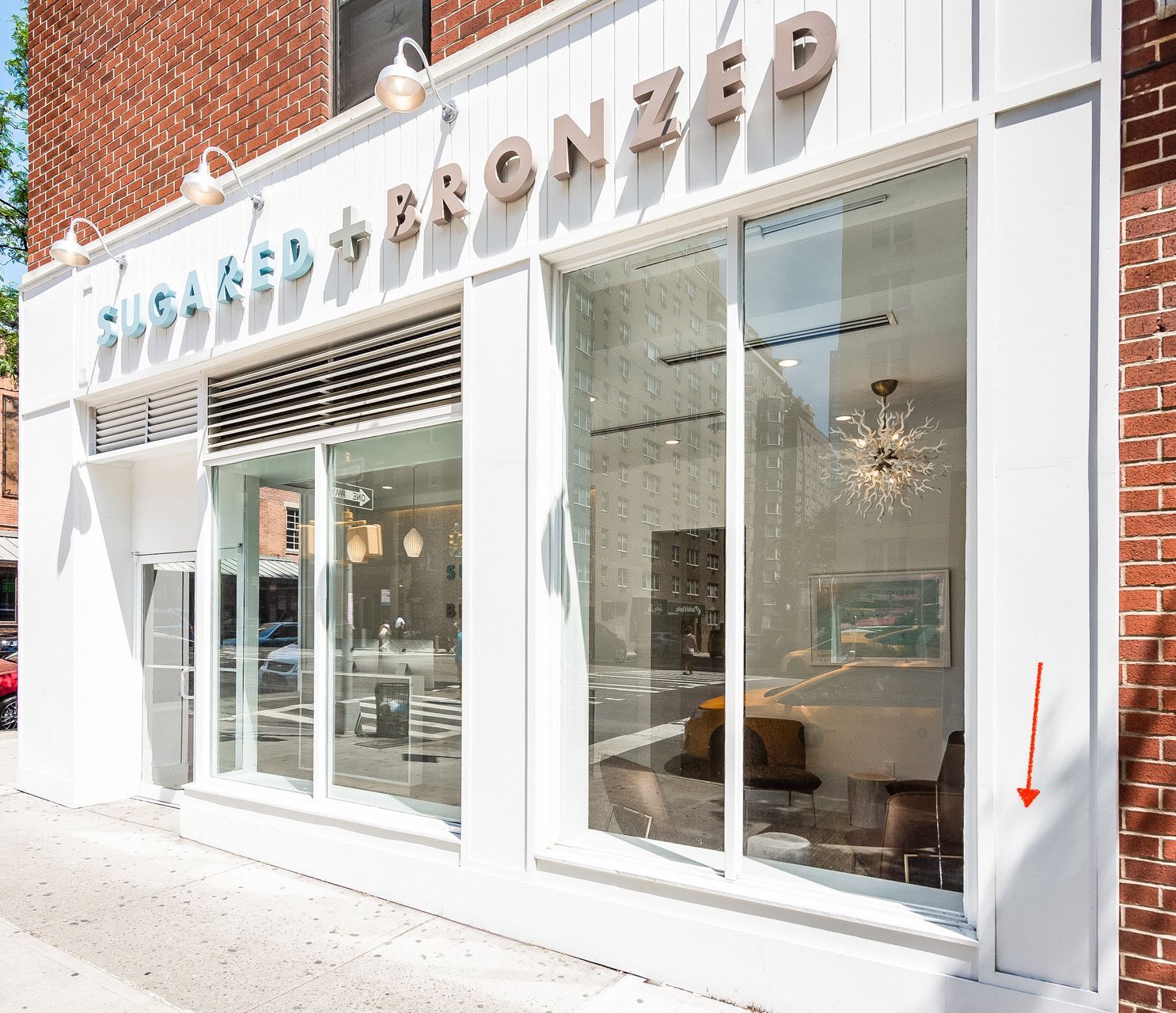 White storefront with large windows and a sign reading “MISTER BRONZE” on a brick building.