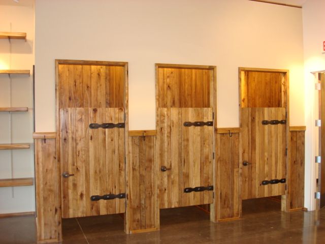 Three rustic wooden half-doors in a row against a beige wall inside a room