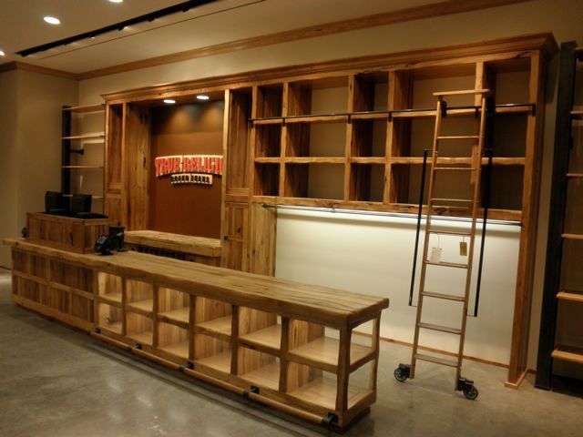 Wooden stage set with built-in shelves, long bench, and a wheeled ladder in a theater workshop