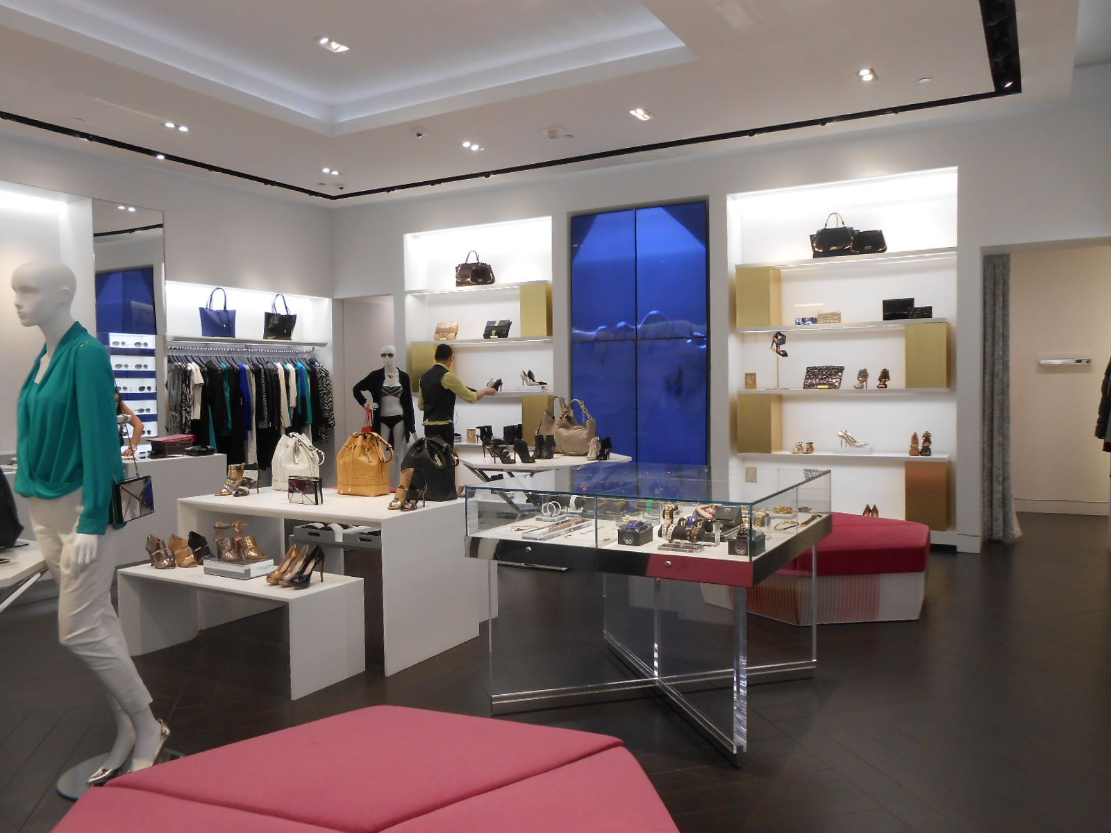 Bright boutique clothing store with mannequins, shelves, and display tables in a modern white interior