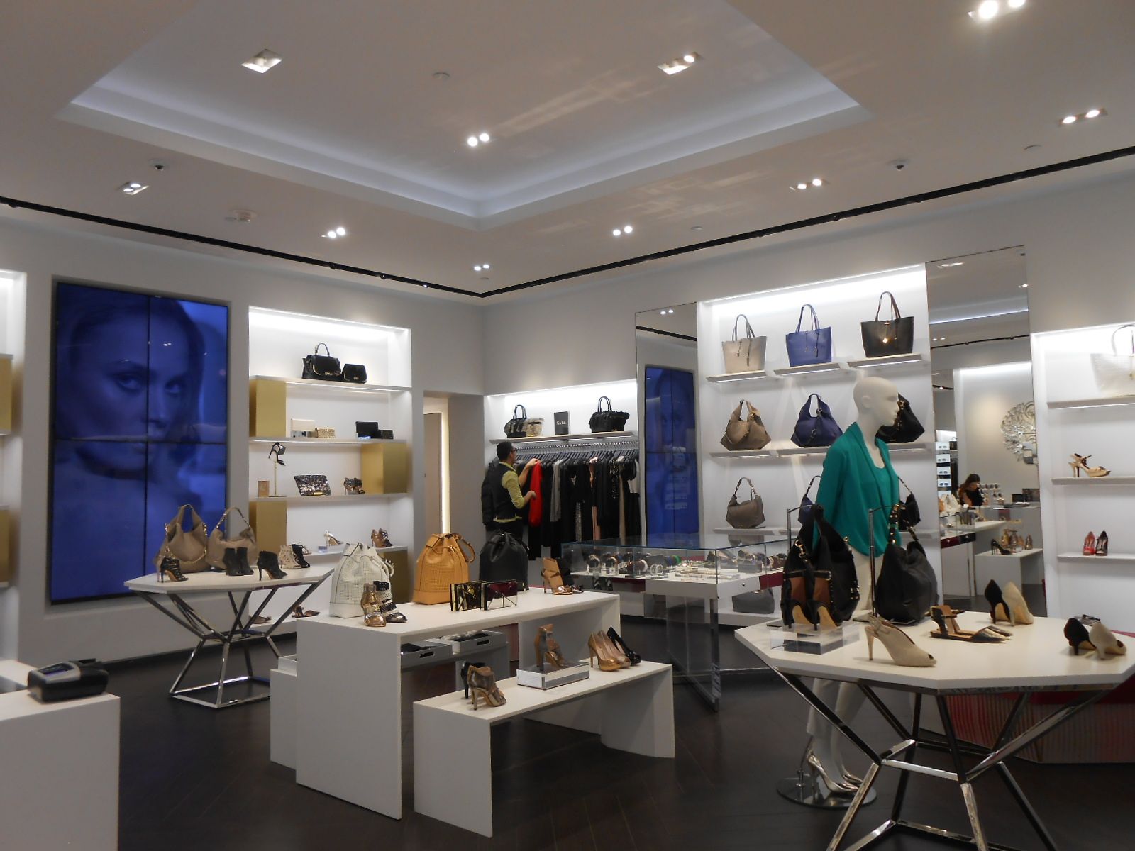 Modern boutique interior with shelves of handbags, shoes, clothing, and accessories under bright lights