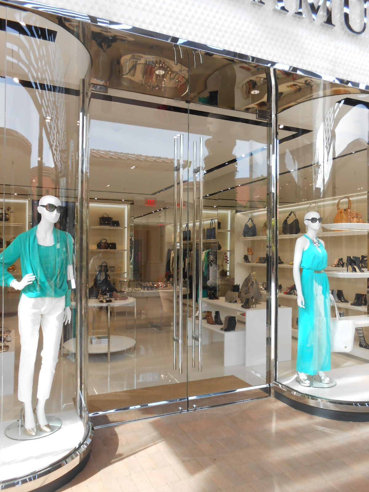 Storefront with two mannequins in teal outfits behind glass doors
