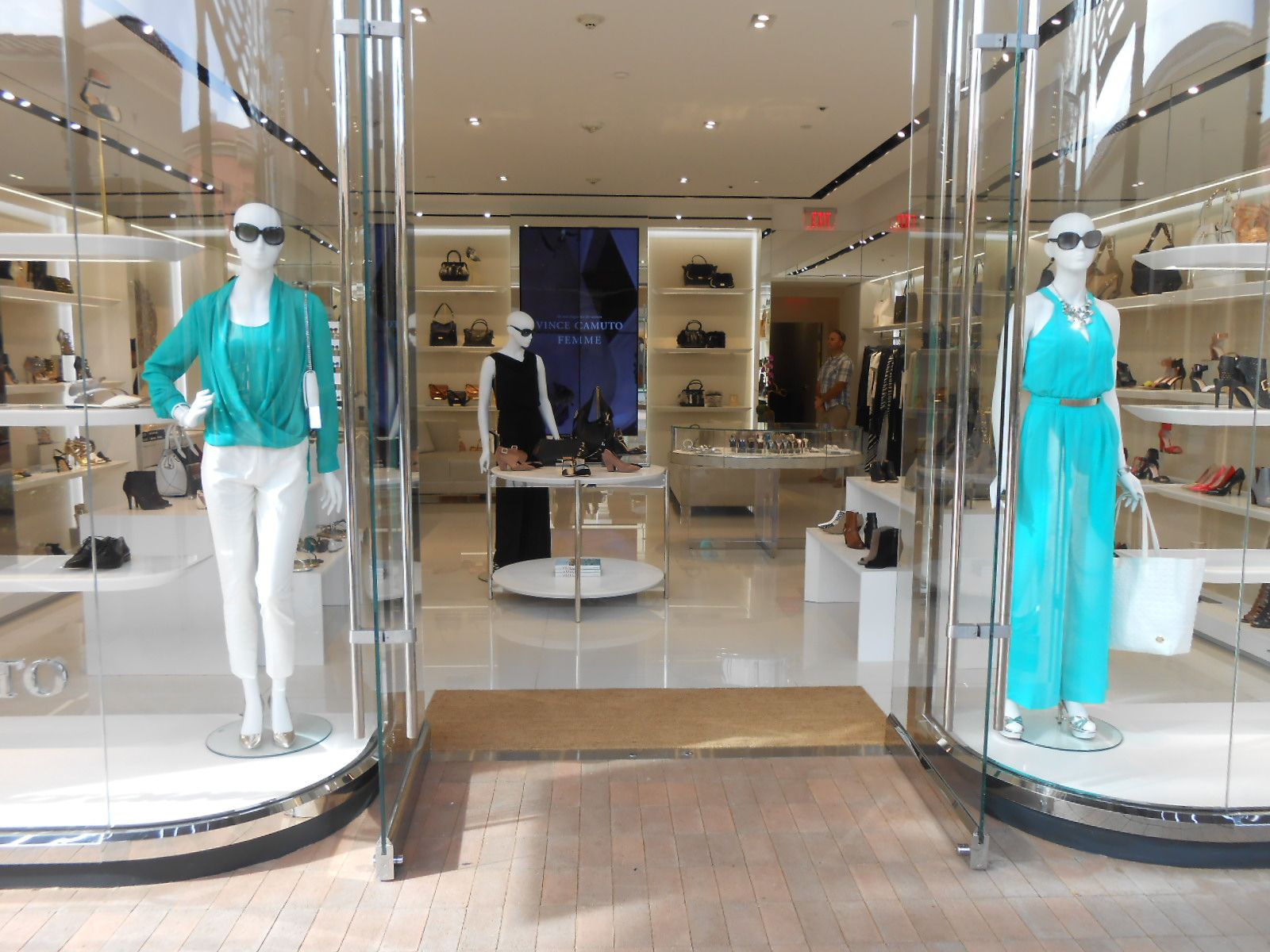 Mannequins in turquoise outfits display clothing in a bright boutique storefront.