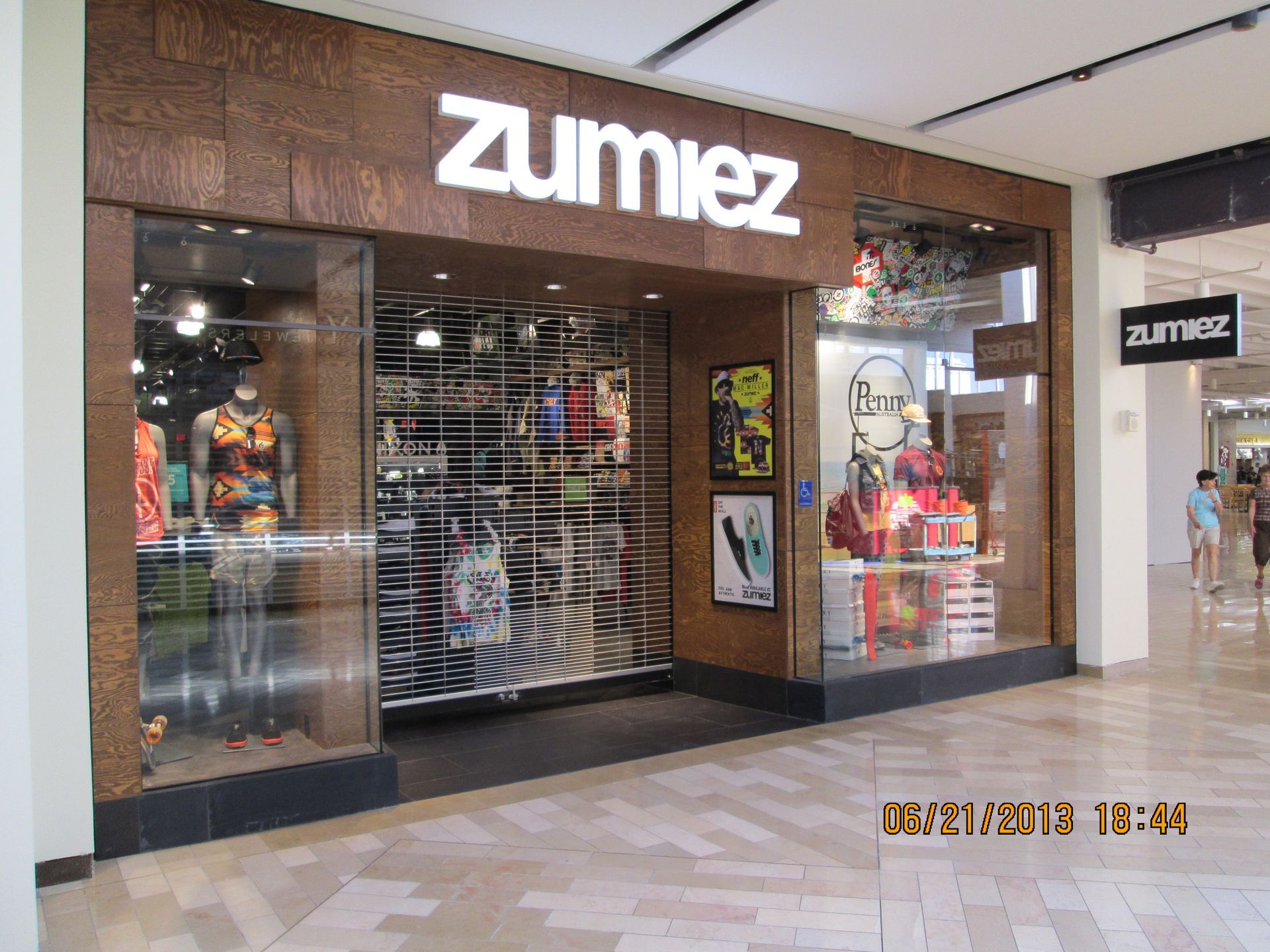 Zumiez storefront in a shopping mall, with mannequins and clothing displays behind the glass.