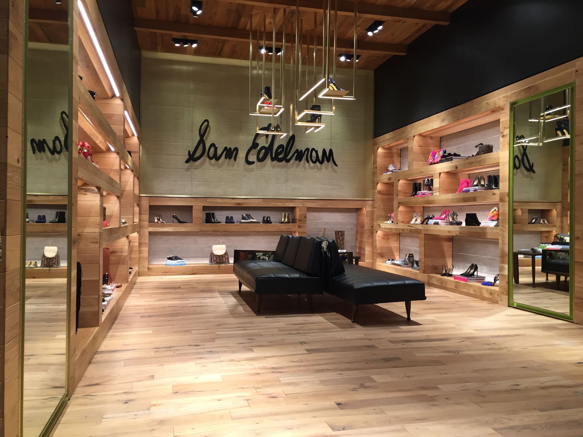 Modern boutique interior with wooden shelves, black seating, and a large 
