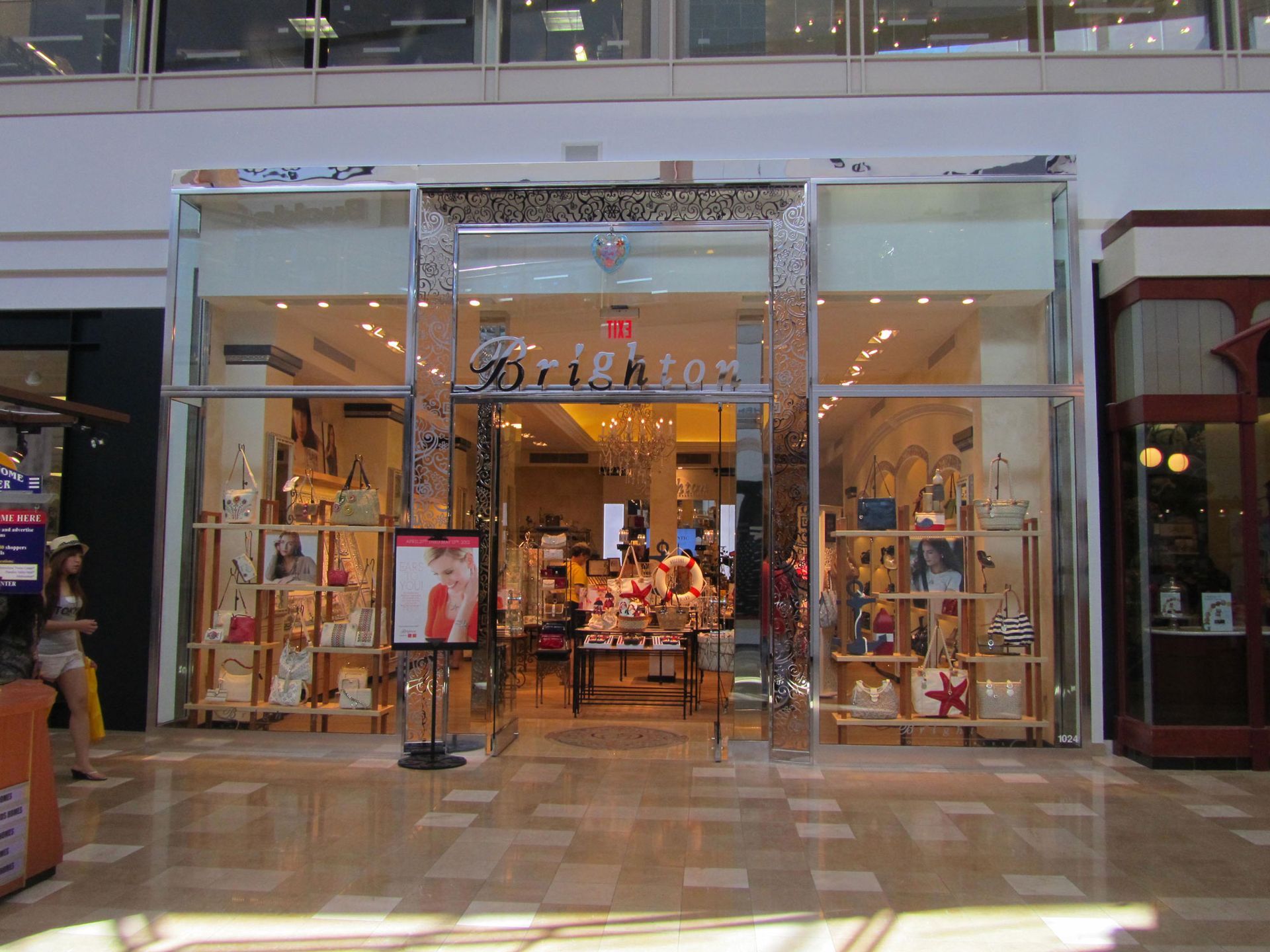 Storefront display of a brightly lit boutique in a shopping mall, with clothing and accessories in the windows