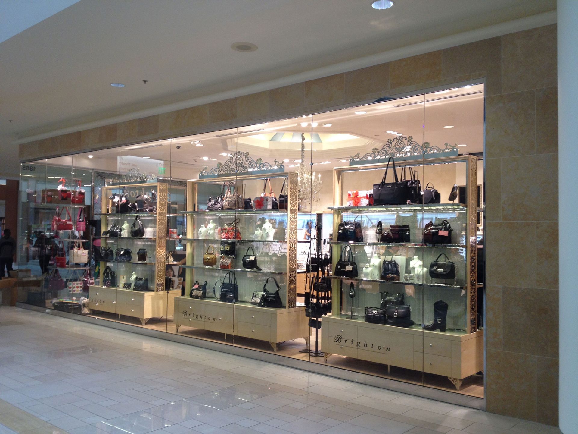 Glass storefront displaying handbags and accessories in a shopping mall corridor