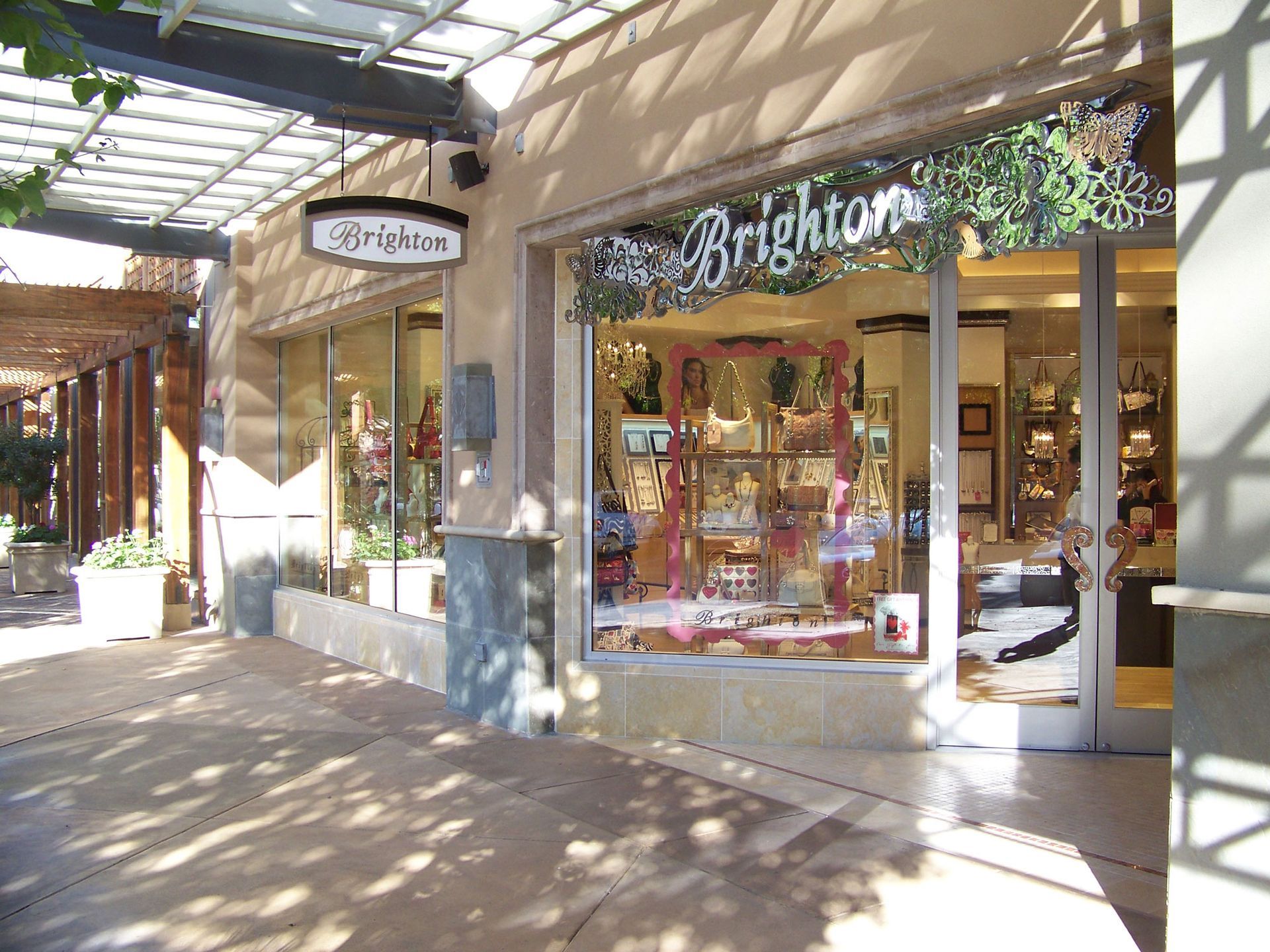 Outdoor shopping arcade with a Brighton storefront, glass windows, and sunlit walkway