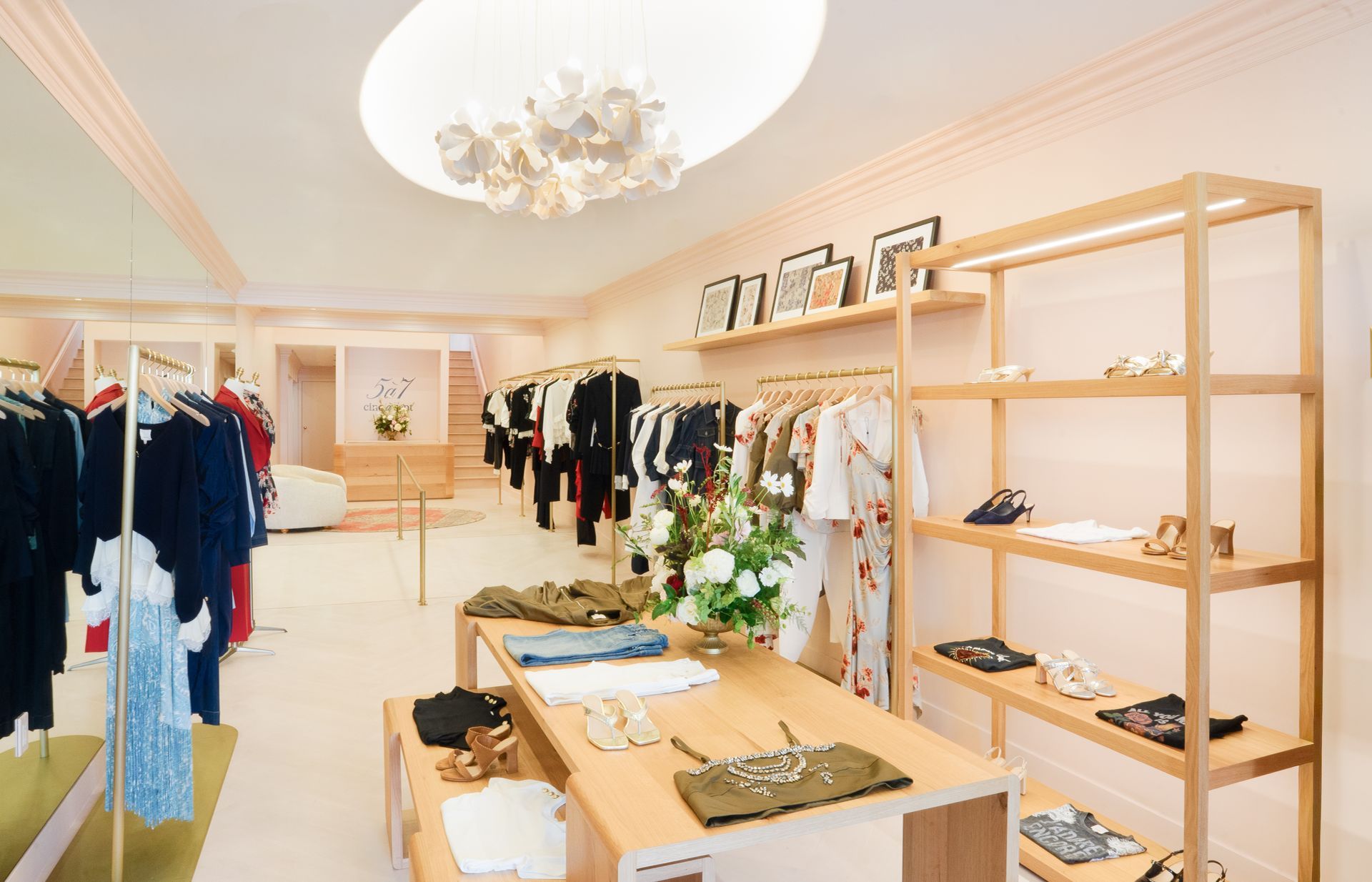 Bright boutique interior with clothing racks, display shelves, and a central table with folded garments and flowers