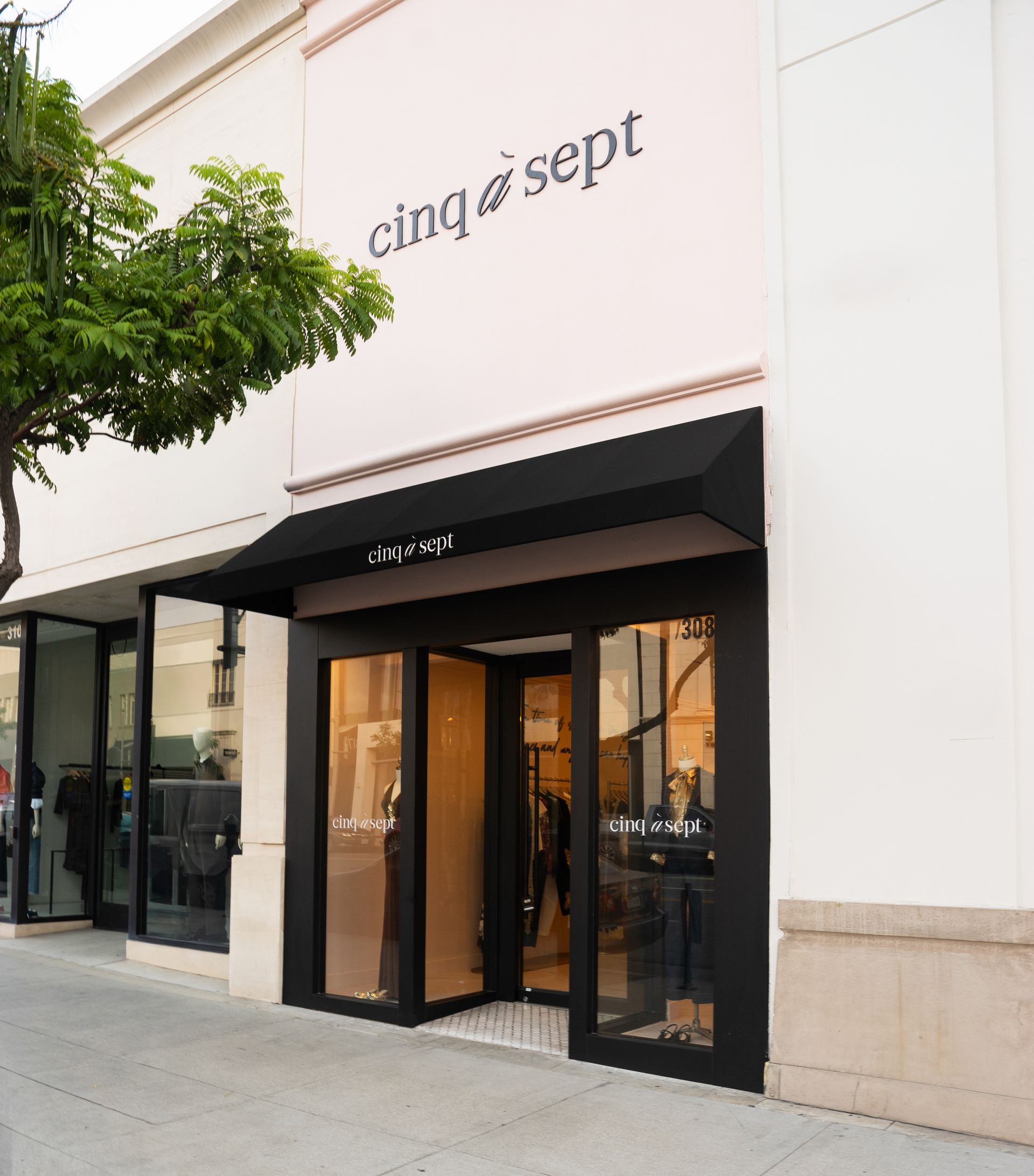 Storefront with black awning and glass doors, labeled “cinq à sept,” on a sidewalk.