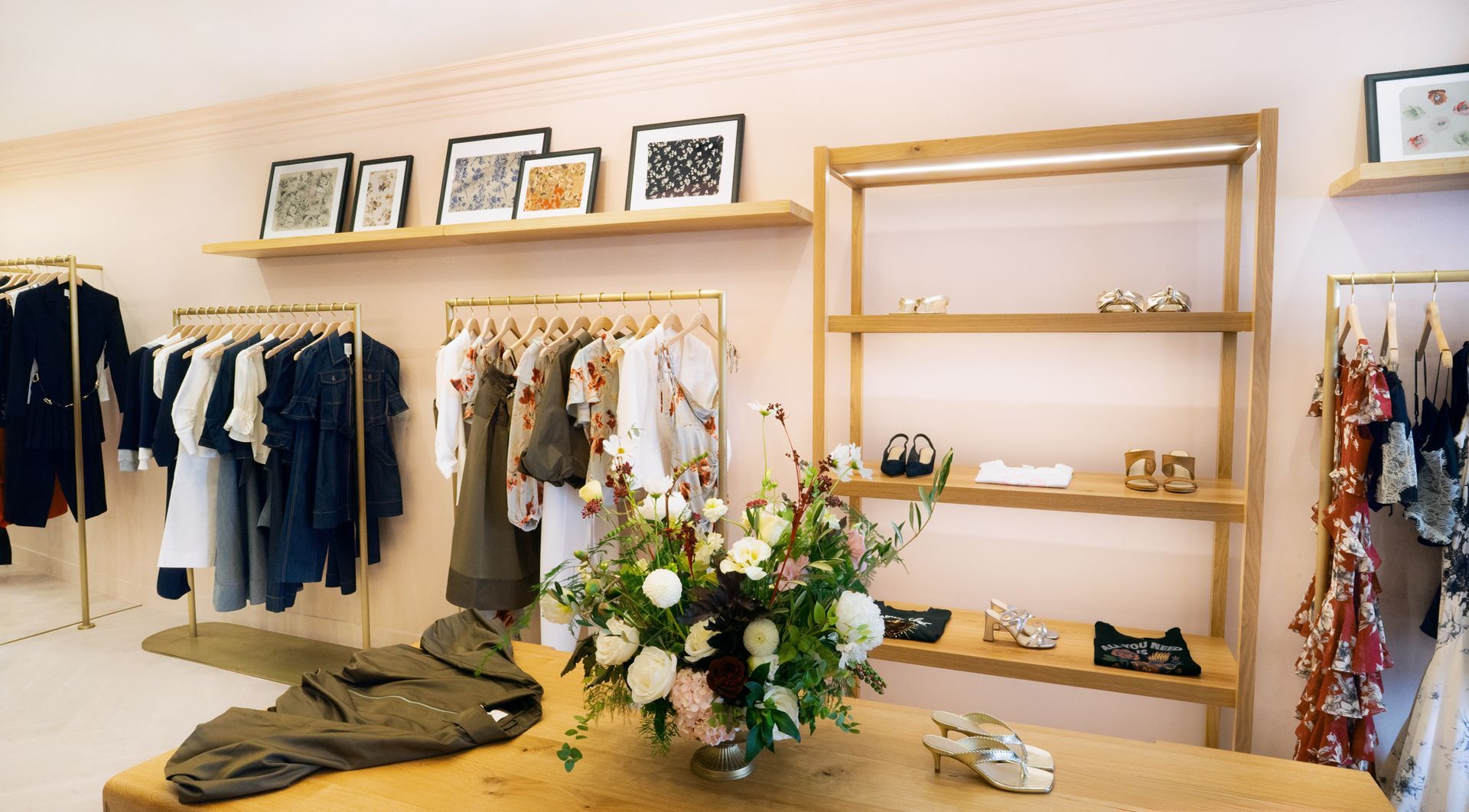 Boutique clothing store with racks of apparel and a central table of flowers and accessories