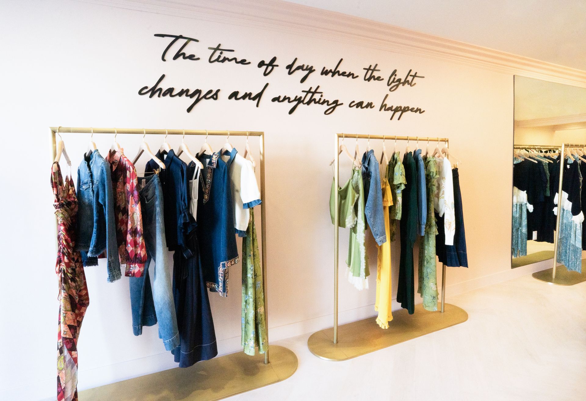 Clothing racks with colorful garments in a bright boutique under a wall quote about time and change