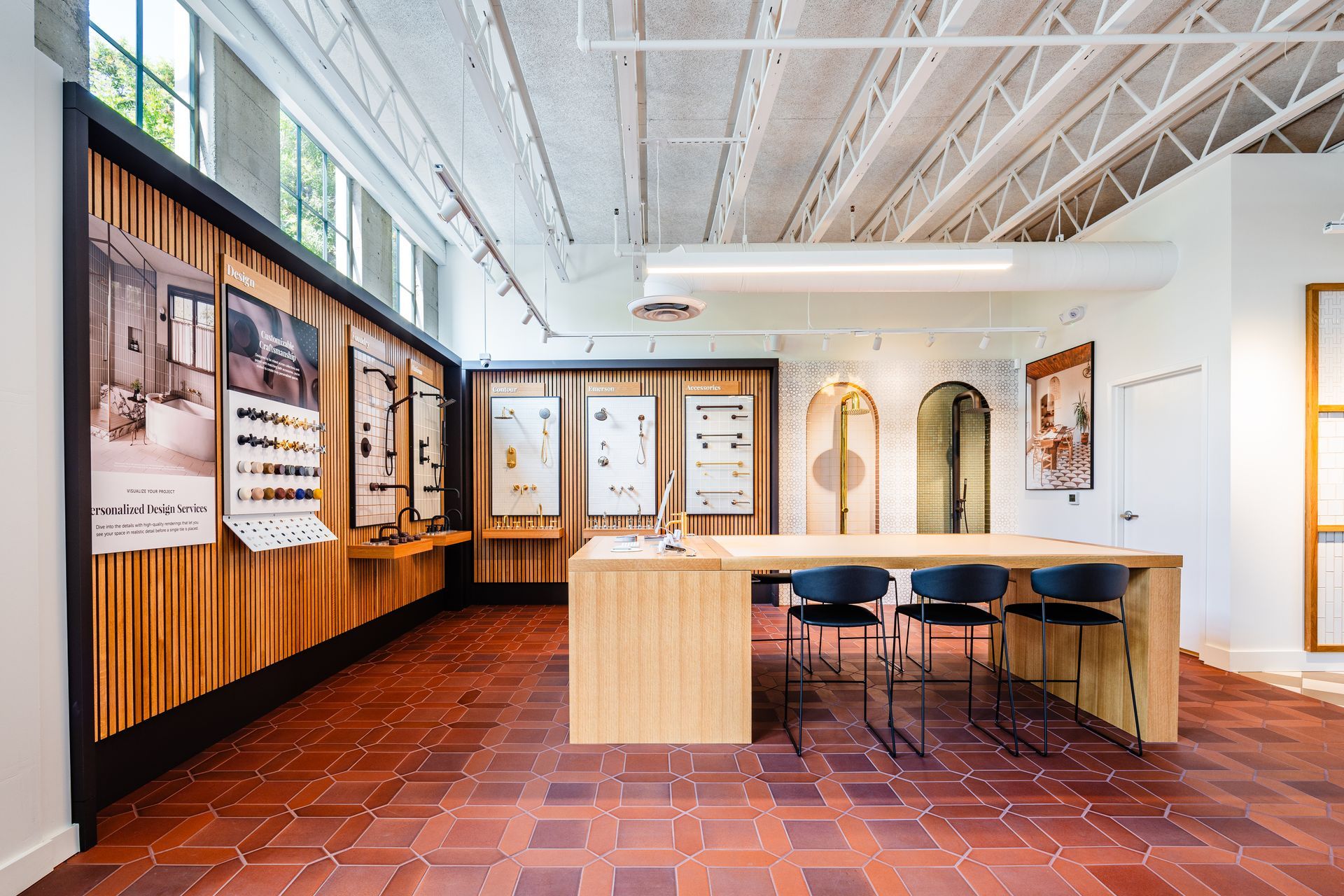 Modern gallery showroom with wood-paneled displays, terracotta tile floor, and a central table with stools