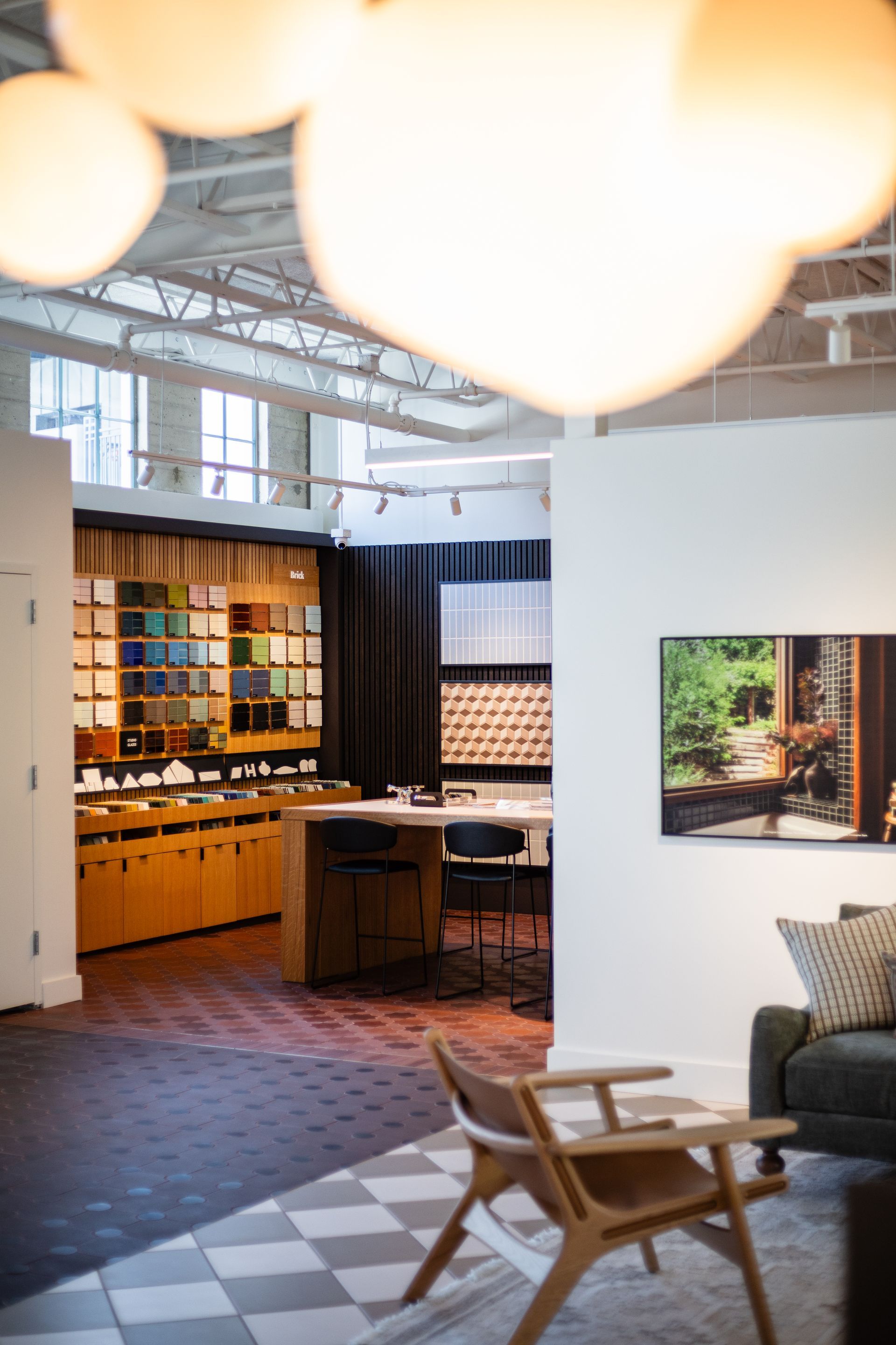 Bright modern café interior with wood counter, pendant lights, checkered floor, and chairs near a wall photo
