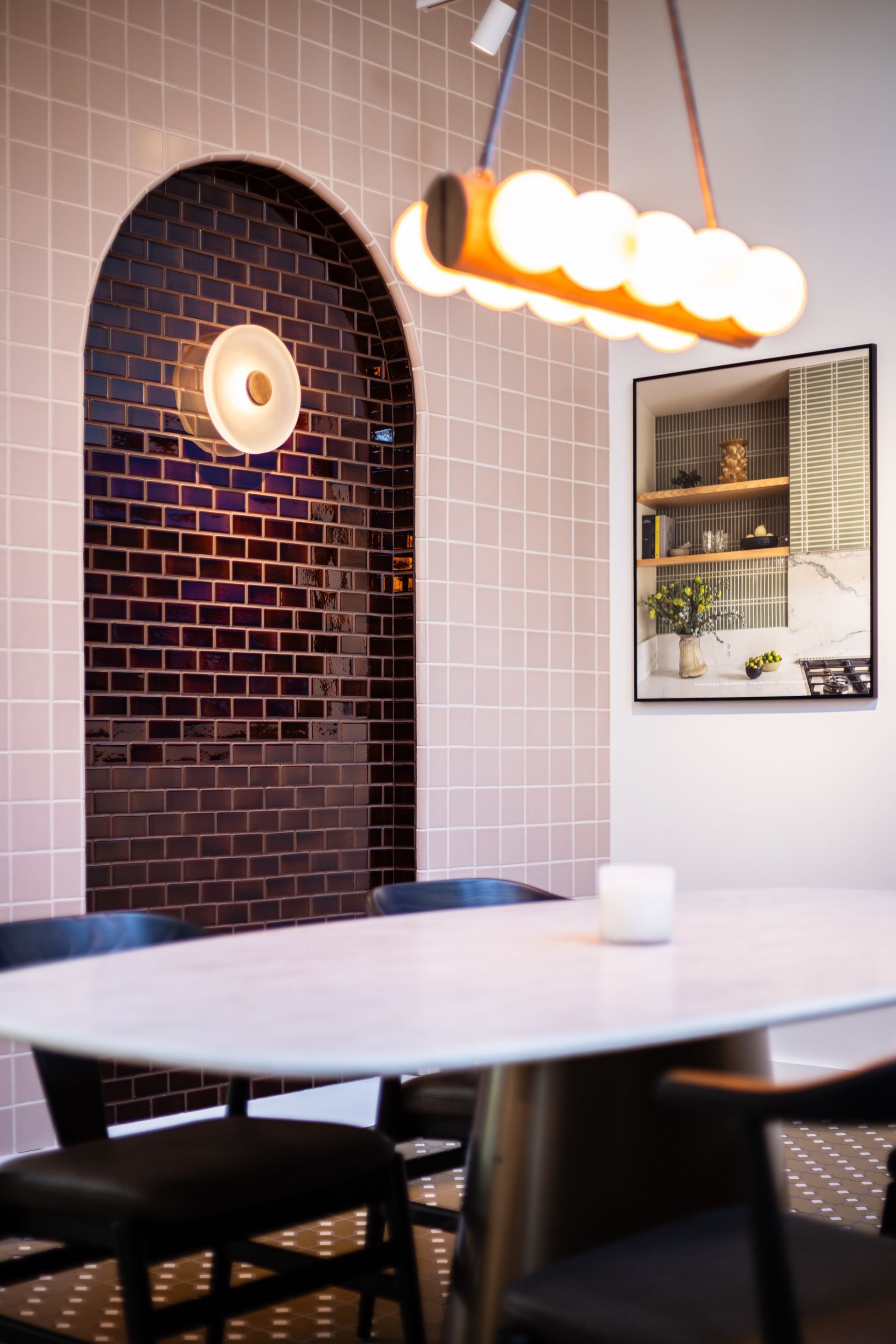 Modern café interior with arched brick wall, round table, and hanging globe lights